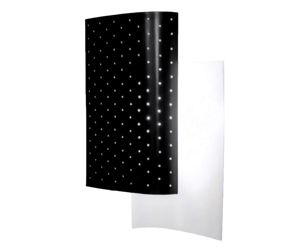 This lamp consists of 2 staggered layers of metal sheets. The light from the light bulb in between the 2 sheets is reflected against a solid steel sheet diffusing the light in the room while a perforated metal sheets in the front indirectly reflects