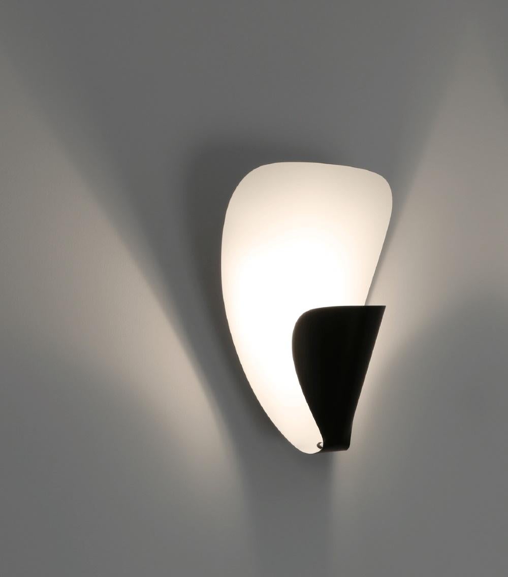 A simple design, elegantly executed with subtle curves. The bulb is wrapped and hidden from view while the light is projected out. Enameled aluminium.
