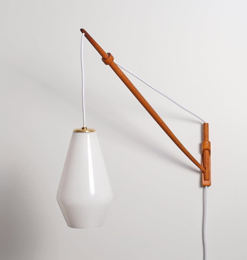 Large oak wall lamp by A. Bank Jensen & Kjeld Iversen for Louis Poulsen, 1950s. The lamp can be adjusted to the left and right and up and down simply by pulling or releasing the wire. Beautiful milk glass shade with brass fittings. Excellent