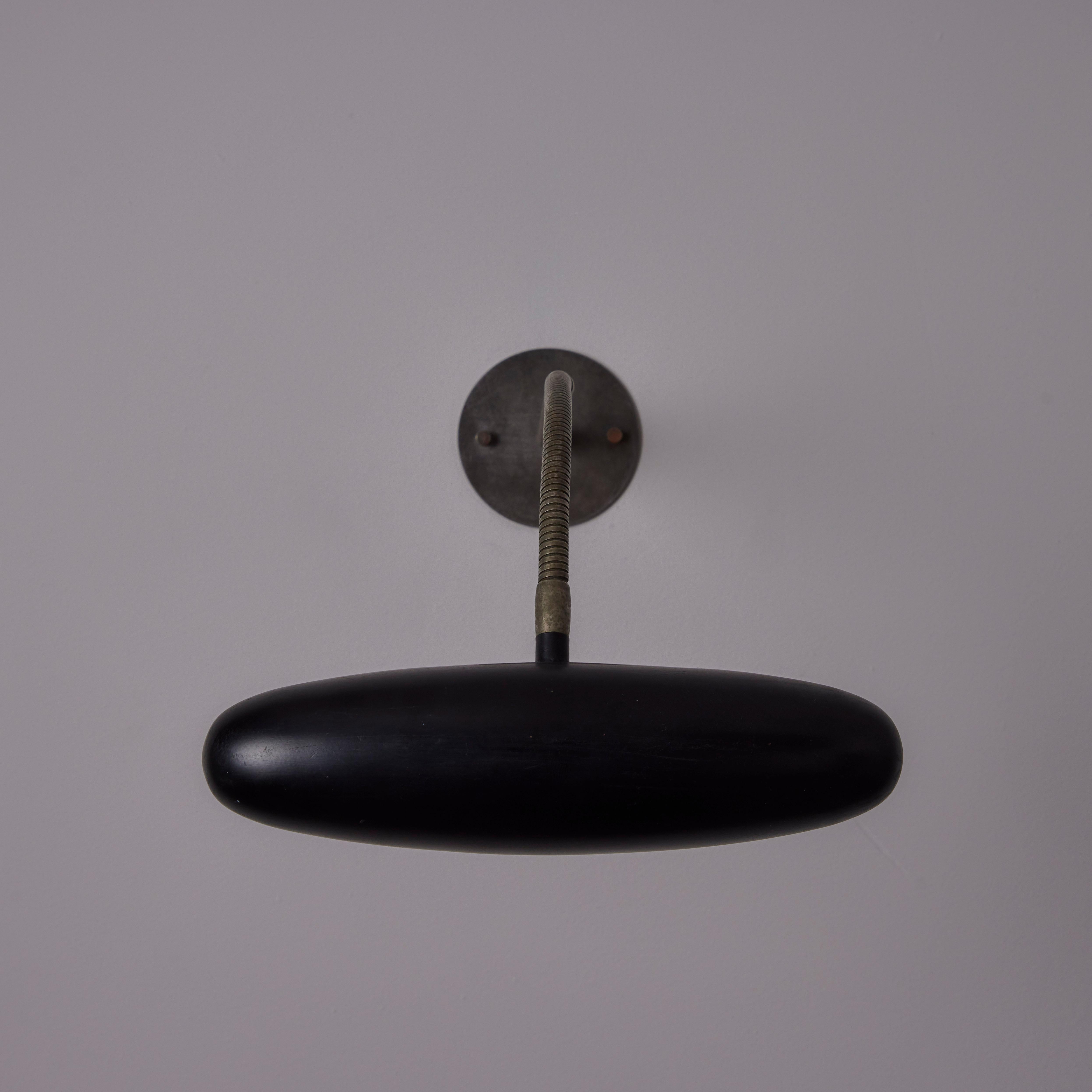 Sconce by Gilardi and Barzaghi. Designed and manufactured in Italy, circa the 1950s. A minimalistic overhead sconce comprising of a black enameled shade and a pewter patinated brass armature. The armature is a flex rod, allowing you to articulate