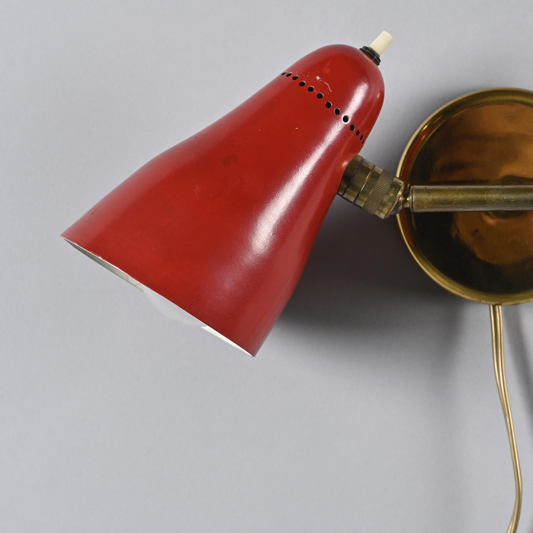 Sconce with a circular base in gilded brass, designed by Giuseppe Ostuni in the 1950s for O'Luce.

The base features a conical stem ending with two joints that hold two conical reflectors in cream lacquered metal. The perforated metal detail adds a