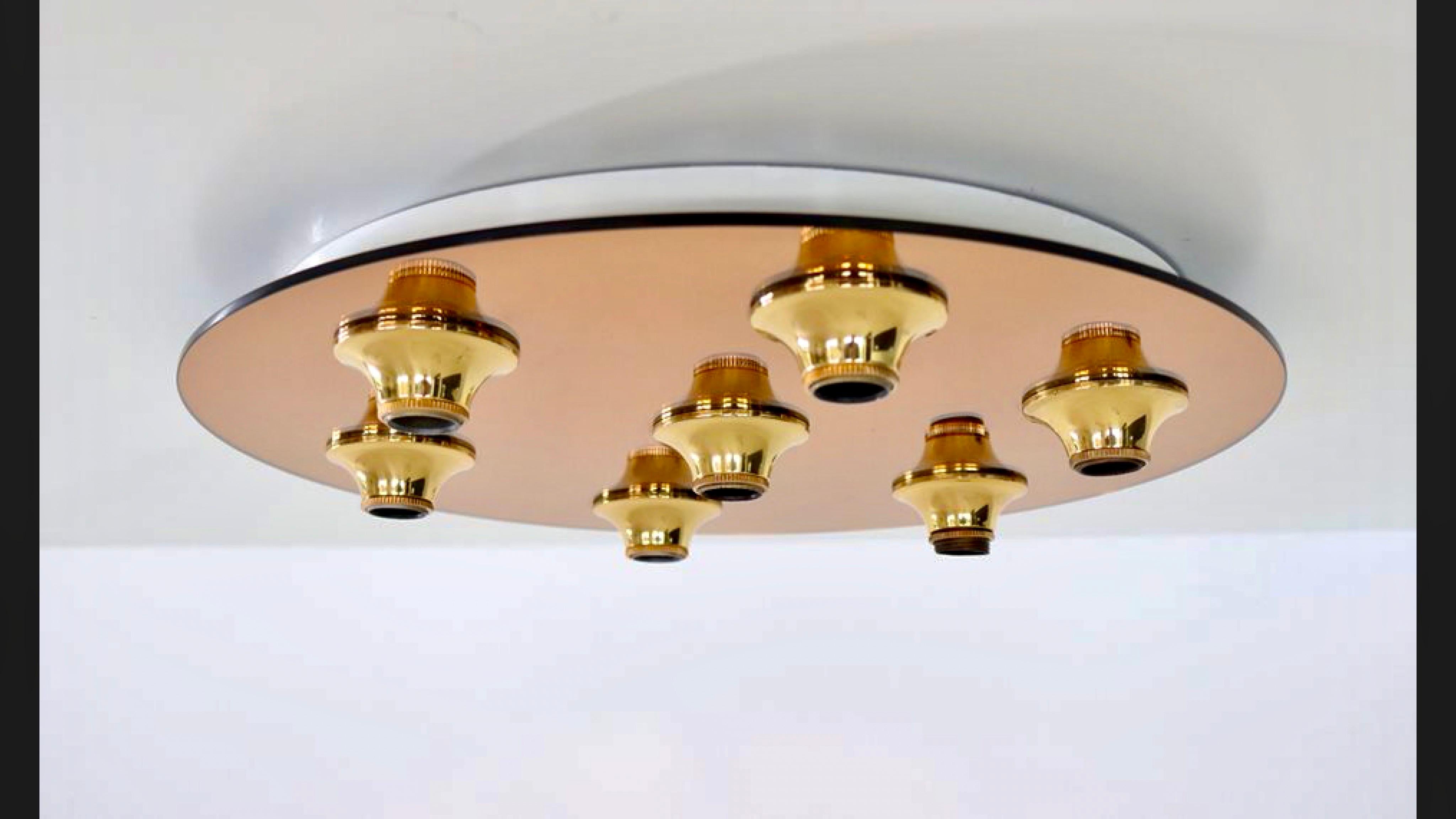 Seven brass cones are mount to mirrored glass to perfectly reflect each bulb, giving the illusion of lights floating in space. 
Measures: Diameter 45 cm.
Depth 6 cm.