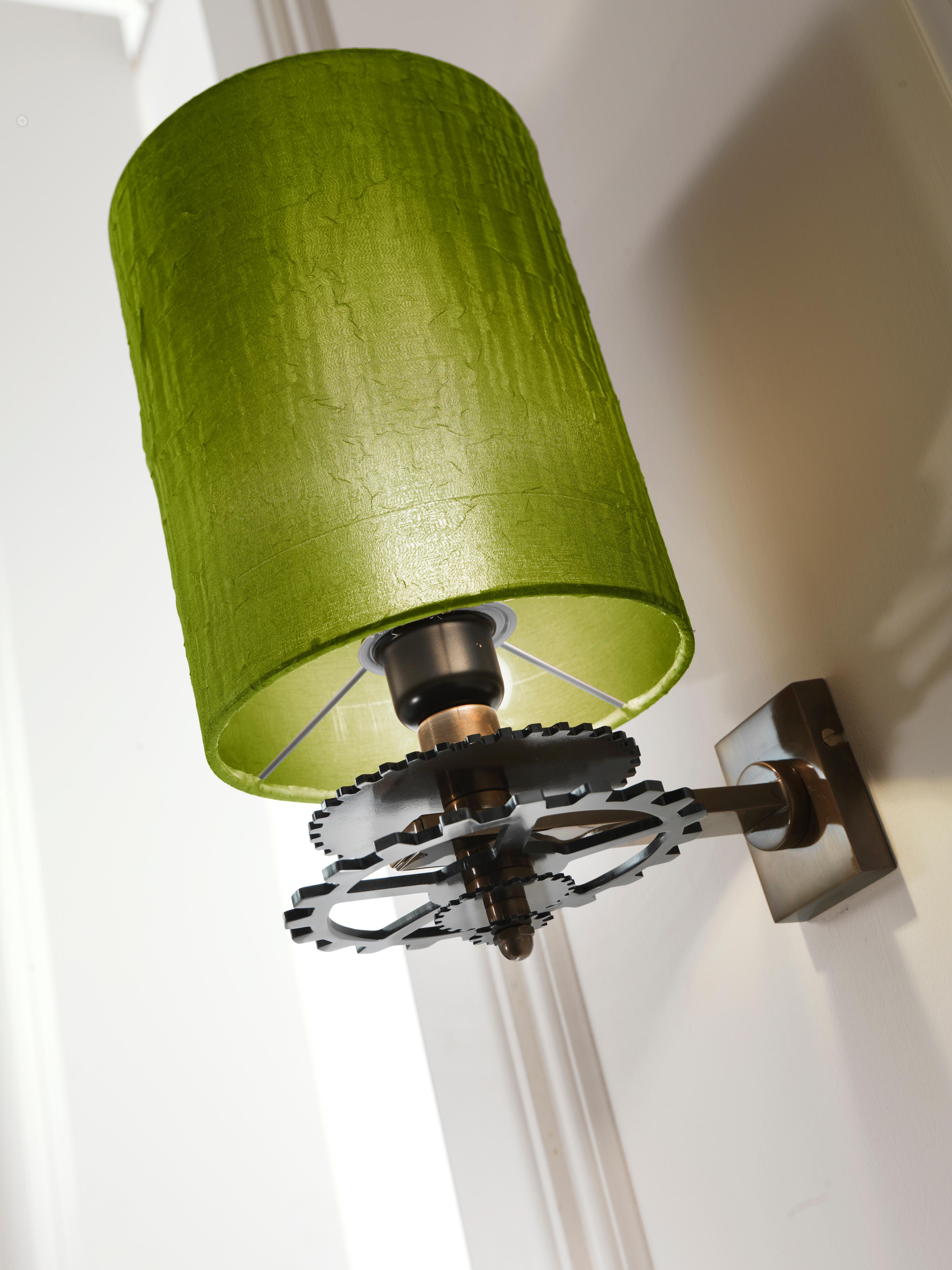 Burnished brass wall lamp with iron gear wheels in pewter finish. Green silk lampshade.