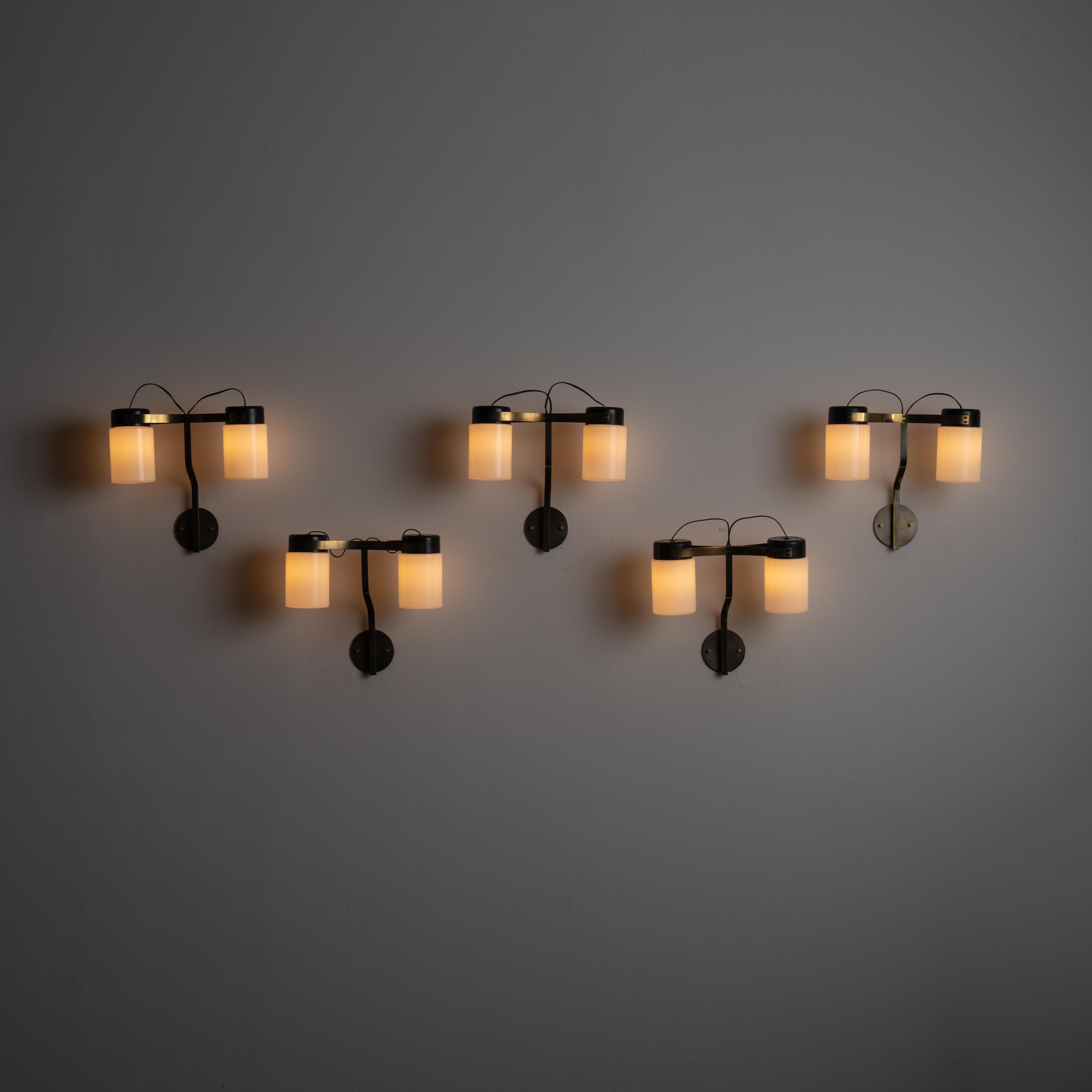 Sconces by Virgina Scoccimarro Galimberti for Adrasteia. Designed and manufactured in Italy, circa the 1950s. Gothic-like double shaded sconces are featured here from Adrasteia. Two screw on opal glass cylinders are hoisted by a burnished brass arm