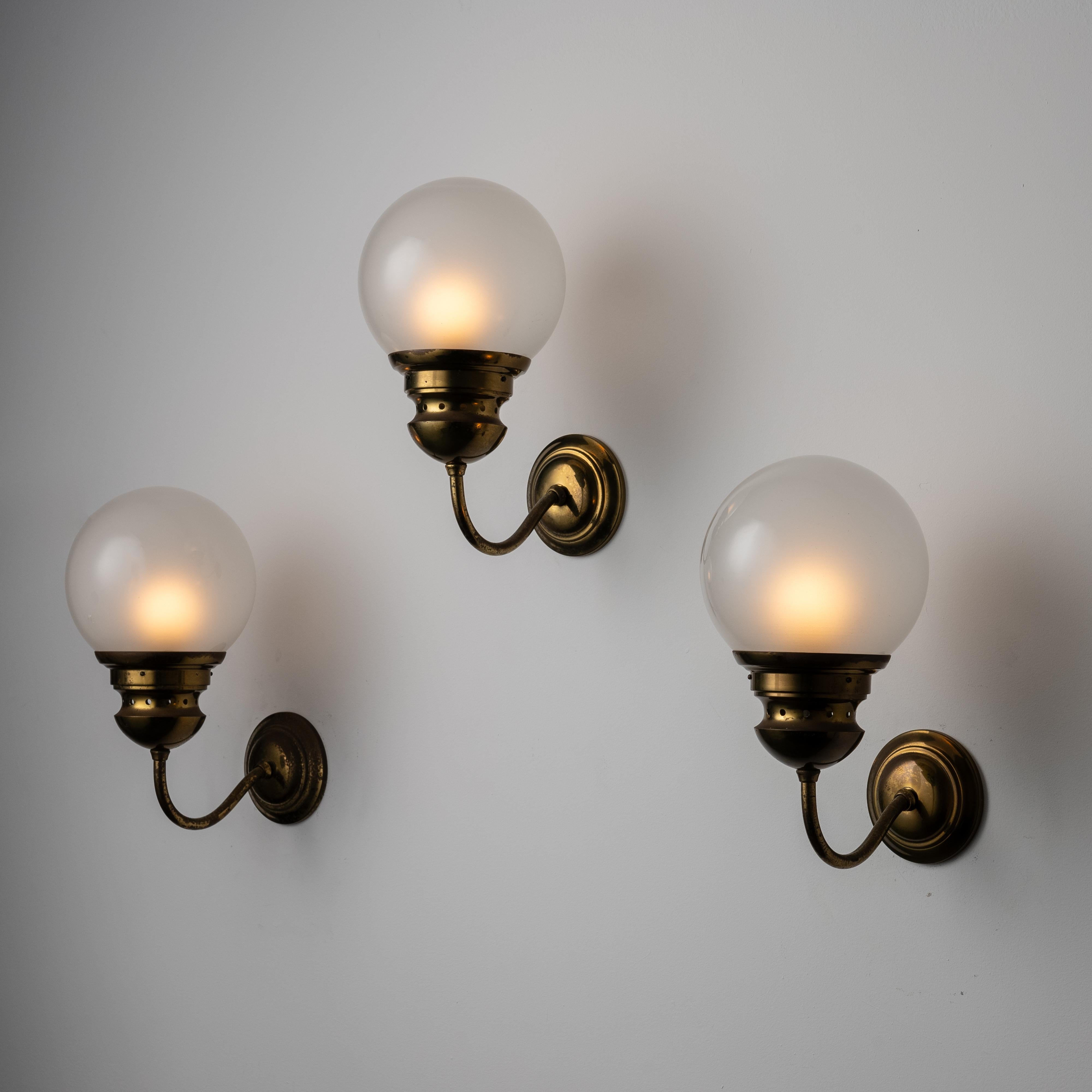 Sconces by Luigi Caccia Dominioni for Azucena. Designed and manufactured in Italy, circa the 1960s. Classical bent arm up-lights comprising of an etched glass globe, sitting atop of a bent brass arm. Each sconce holds a single E27 socket, adapted