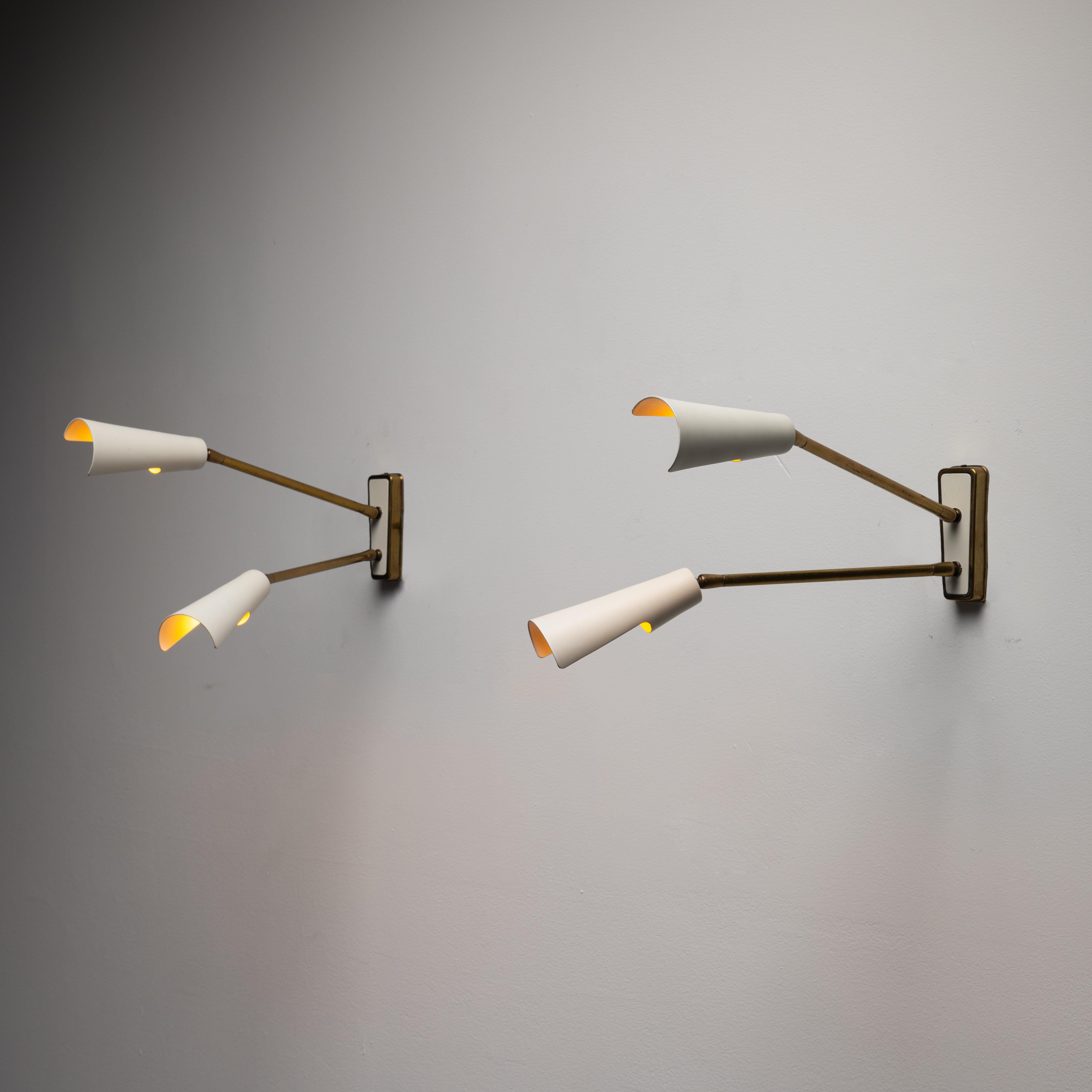 Sconces by Stilnovo. Manufactured in Italy, circa the 1950's. Enameled metal, brass. Original backplates. Arms and shades pivot to various positions. Wired for U.S. standards. We recommend one candelabra 60w maximum bulb per fixture. Bulbs provided