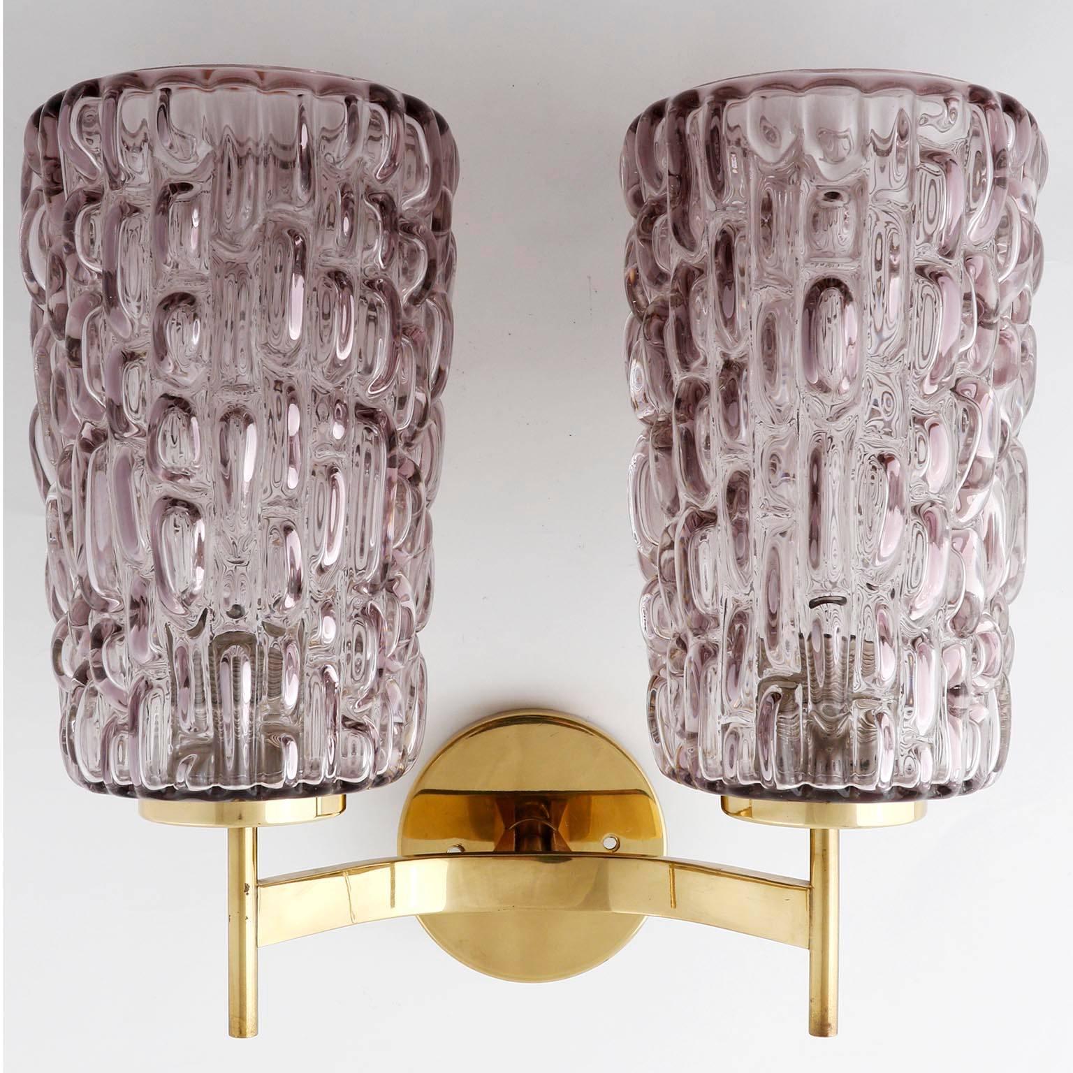 A pair of glass and brass sconces by Rupert Nikoll, Austria, manufactured in midcentury, circa 1950 (late 1950s or early 1960s).
Each sconce is made of a brass frame with a small wood cap at the bottom and two textured glass lamp shades in a rose /