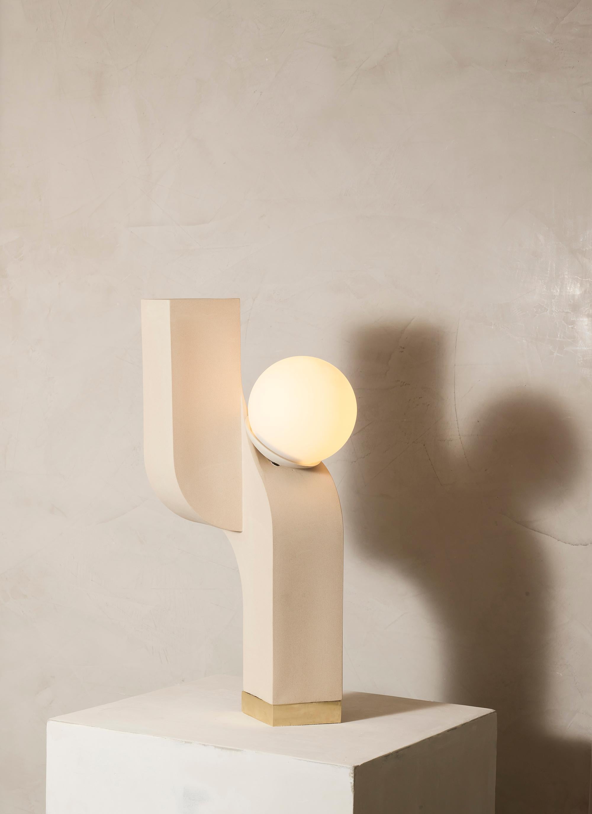 Defying gravity, this cantilever table light is a simple repetition of form and displays dynamic views from
all sides. This table light is slipcast in ceramic and sits atop a satin brass base.
 
Made in NYC.