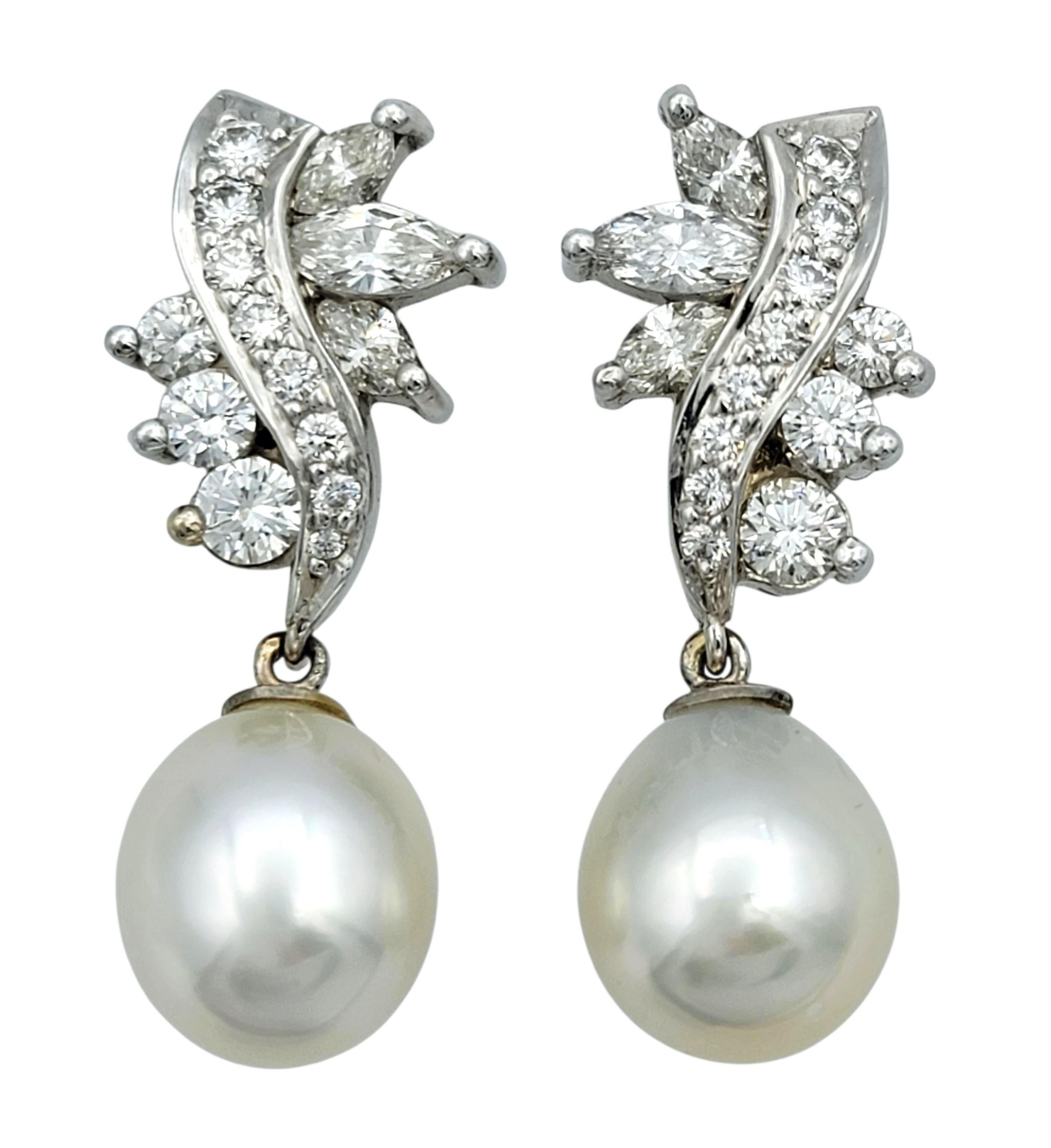 Ces superbes boucles d'oreilles en or blanc 14 carats sont une fusion éblouissante d'élégance classique et de design affirmé. La partie supérieure est un riche arrangement de diamants ronds et de taille marquise qui forment une délicate floraison,