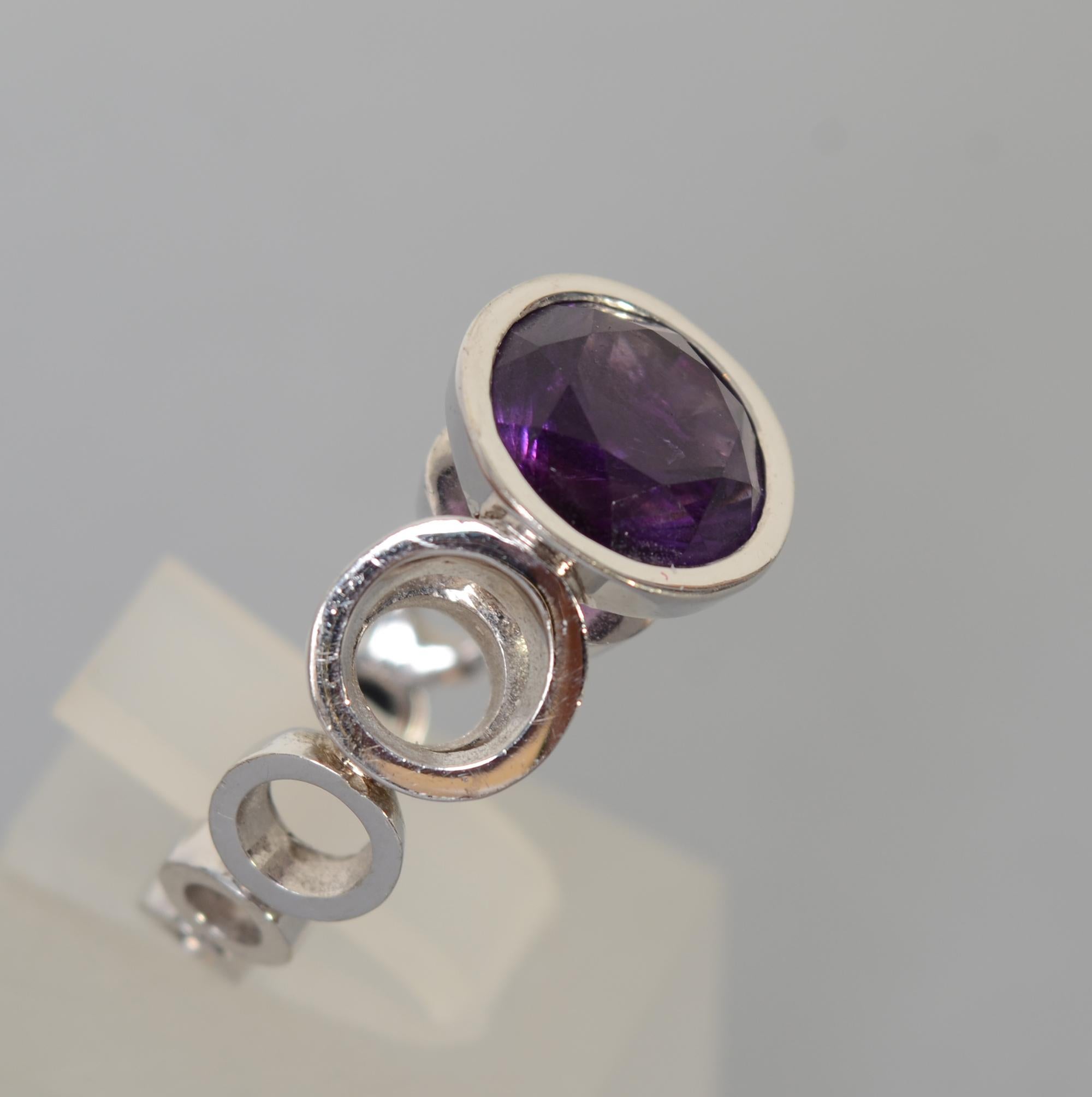 Contemporary amethyst solitaire ring by Scott Gauthier set in 14 karat white gold. The ring consists of graduated open circles with a flat shank. The circle housing the stone is cleverly set above the band to allow light to go all the way through