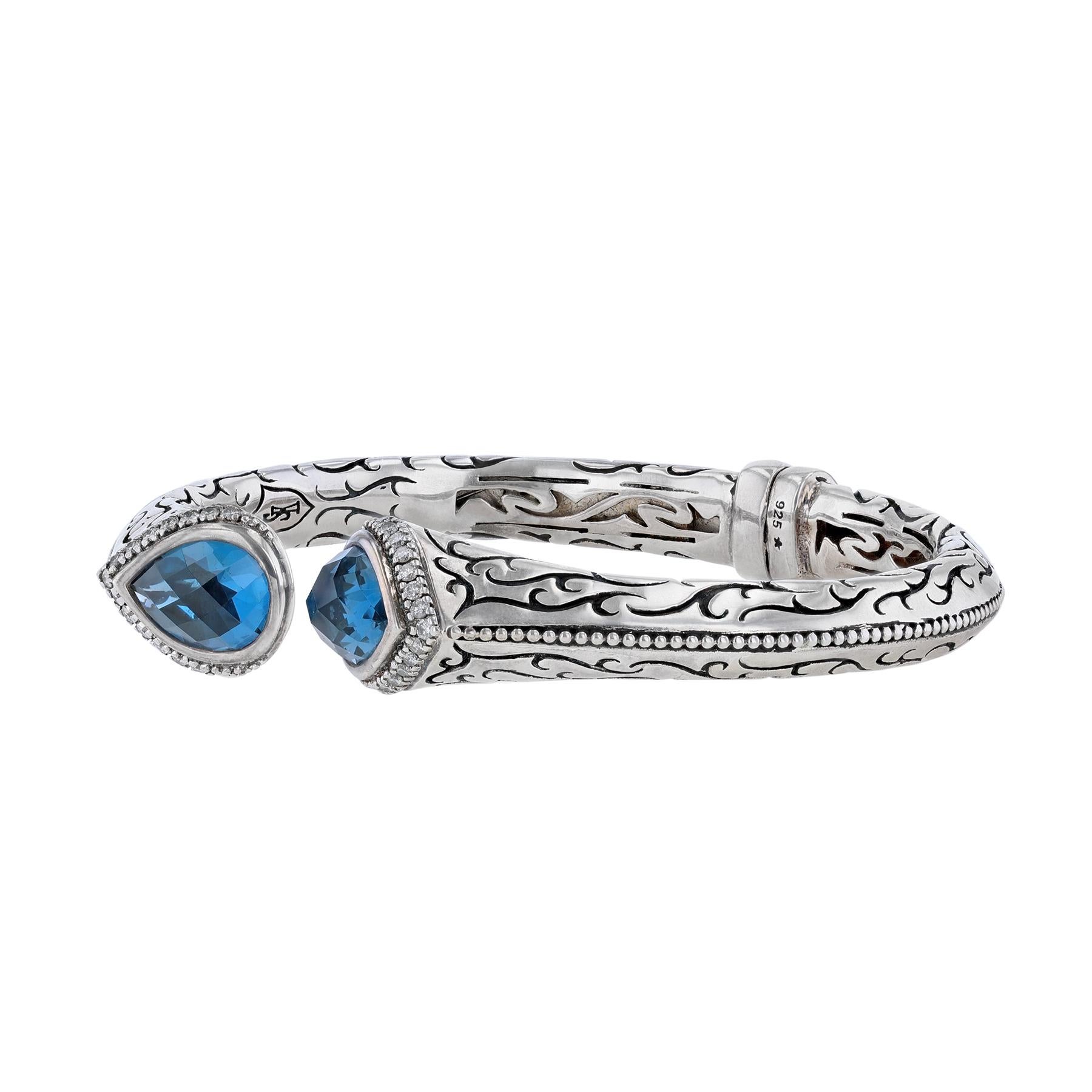 This cuff bracelet is made in sterling silver with 2 London blue topaz and diamonds weighing 0.45 carats.   

