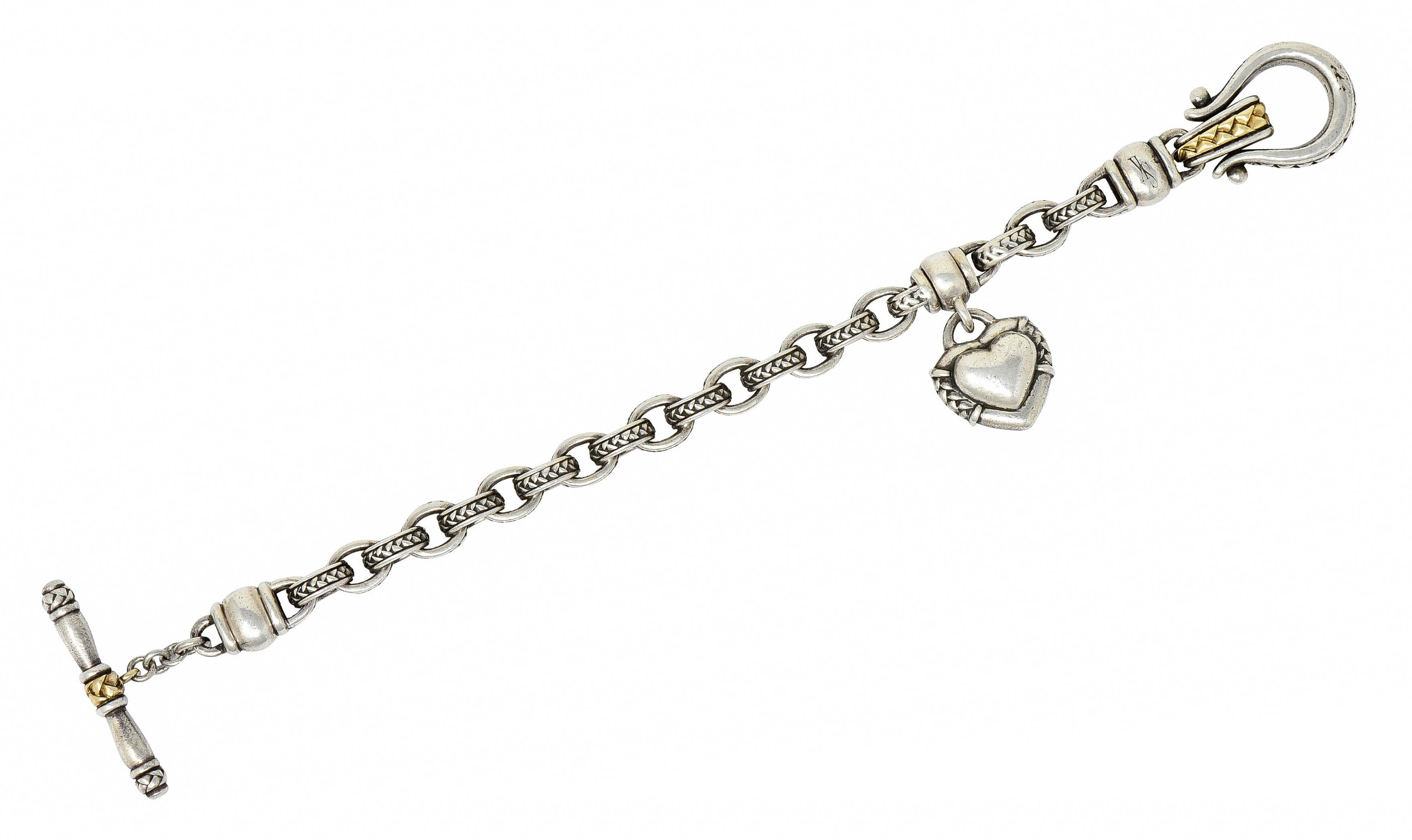Featuring a sterling silver rolo link bracelet with a heart charm

Rolo links are textured as are the sides of the heart

Completed by a stylized toggle clasp and 18 karat gold accents on toggle fittings

Marked 925 750 SK, for sterling silver,18