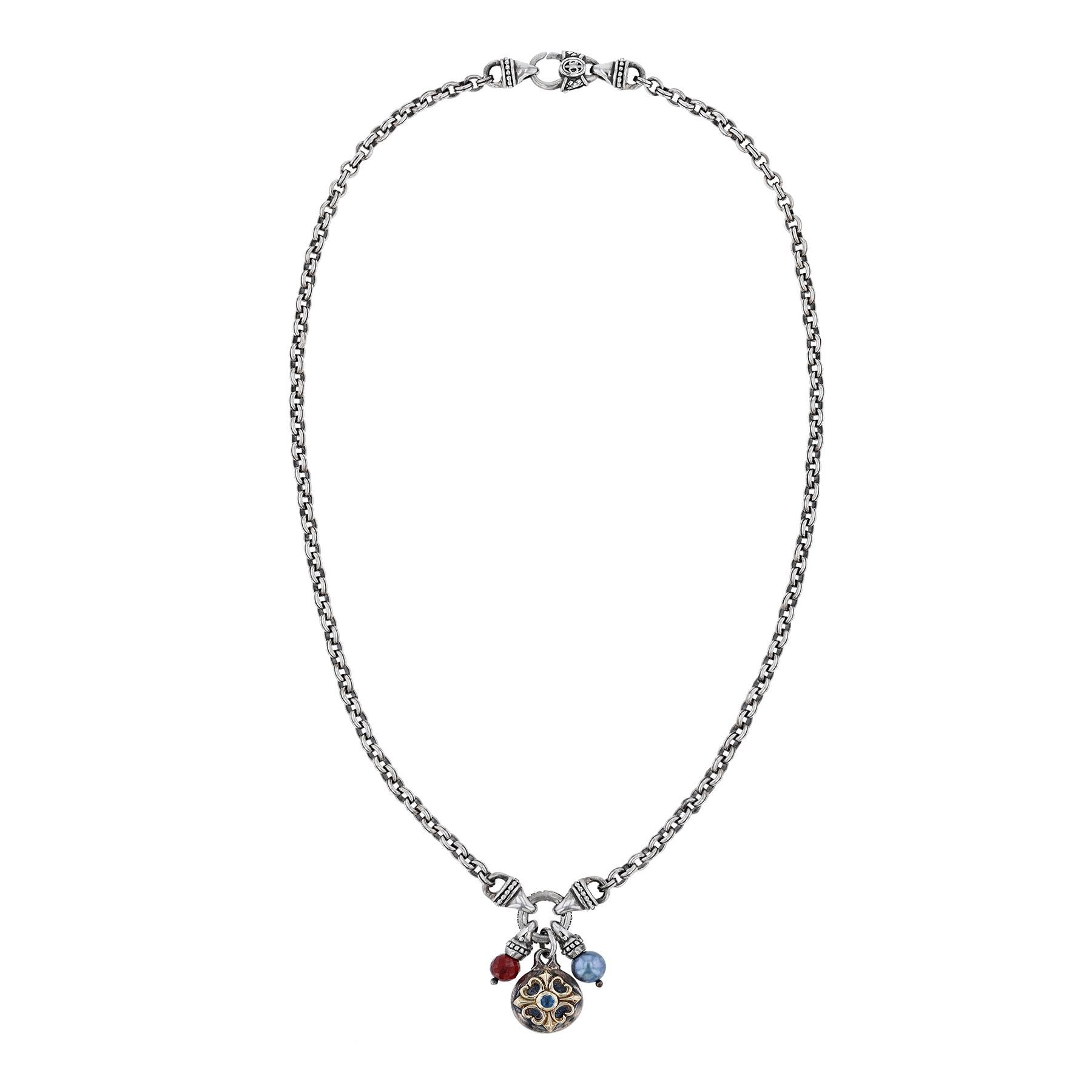 La collana è in argento sterling e oro giallo 18 carati. Presenta tre ciondoli con un topazio blu di Londra, una perla di pavone e una goccia di granato. Su una catena a maglie in argento sterling.