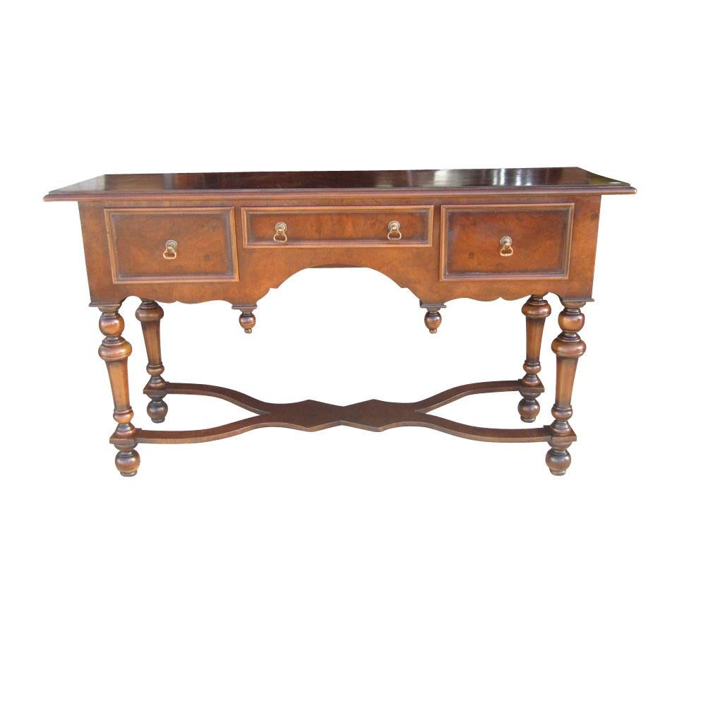 Burled walnut console table in the traditional style manufactured by Scott Thomas. This table features intricate brass pulls and nice detailing on the wood including turned legs and a finely carved leg support. Three small drawers.