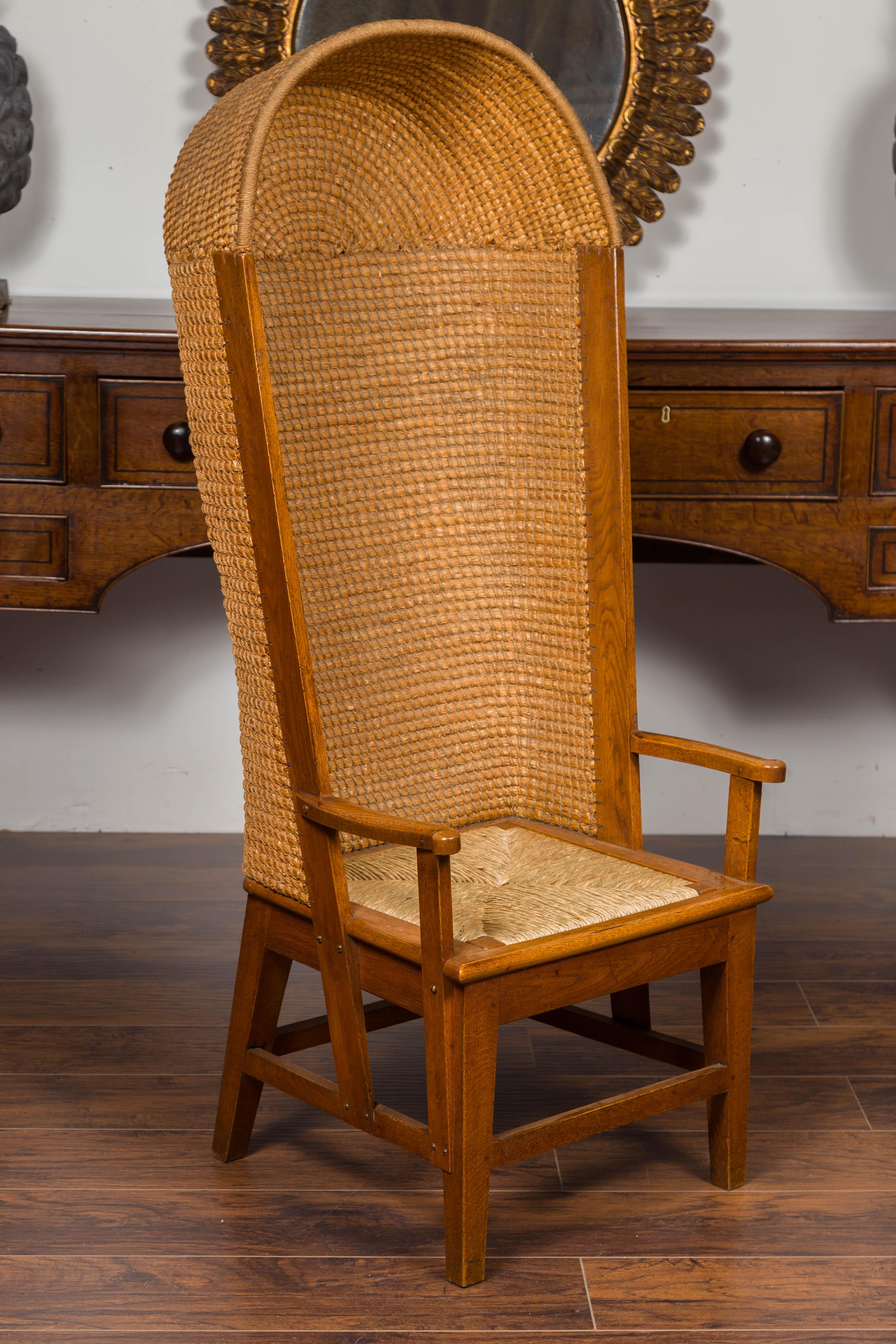 A Scottish Orkney Island canopy chair from the early 20th century with handwoven straw hooded back, rush seat, open arms, tapering legs and side stretchers. Born during the turn of the century in the archipelago of Orkney off of the northern coast