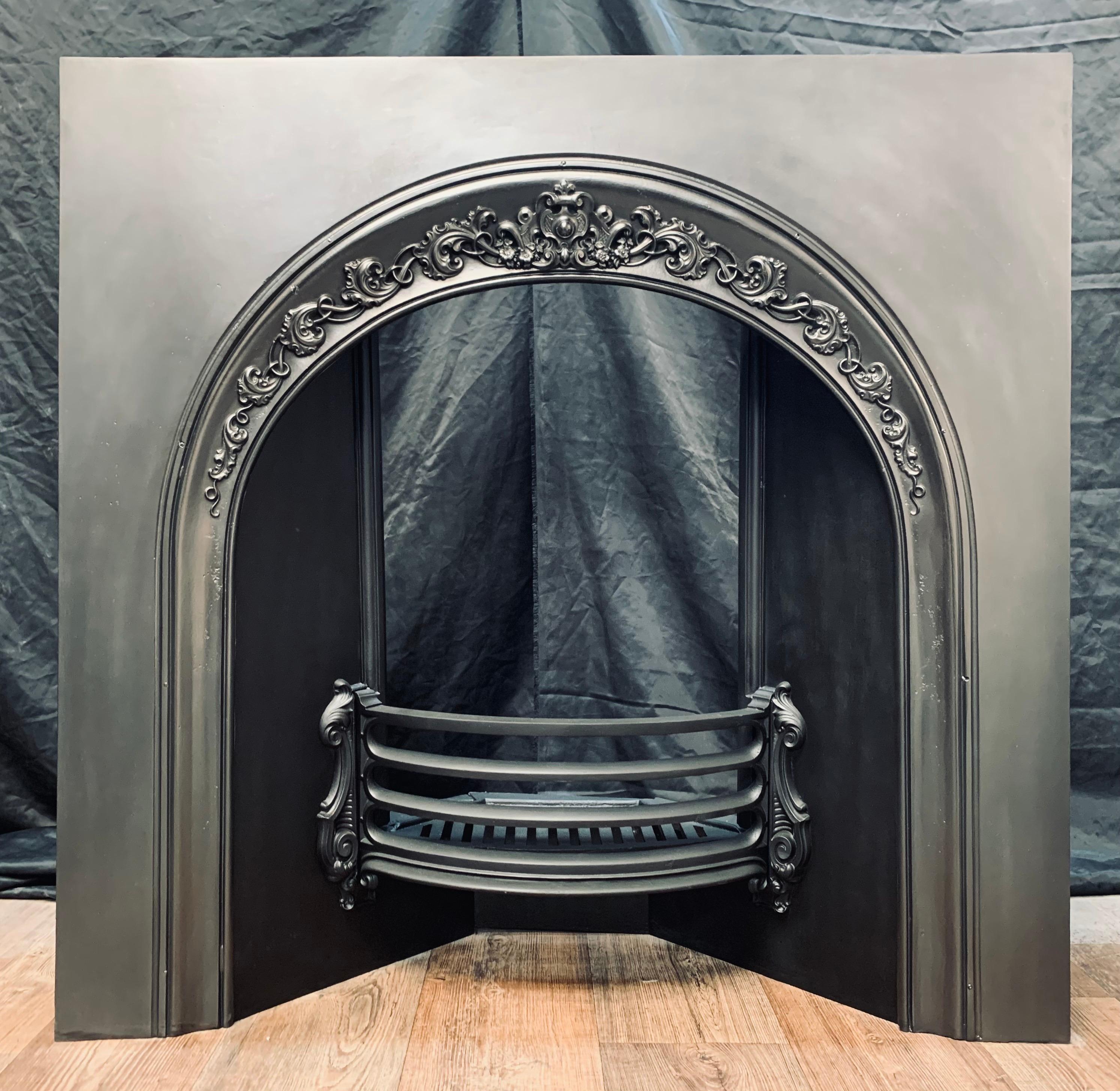 An unusually large mid-19th century Victorian cast iron arched insert from Carron of Falkirk. A generous outer plate with a border cartouche, splayed side returns with mounting points for the curved three barred fire front, the original fire grate
