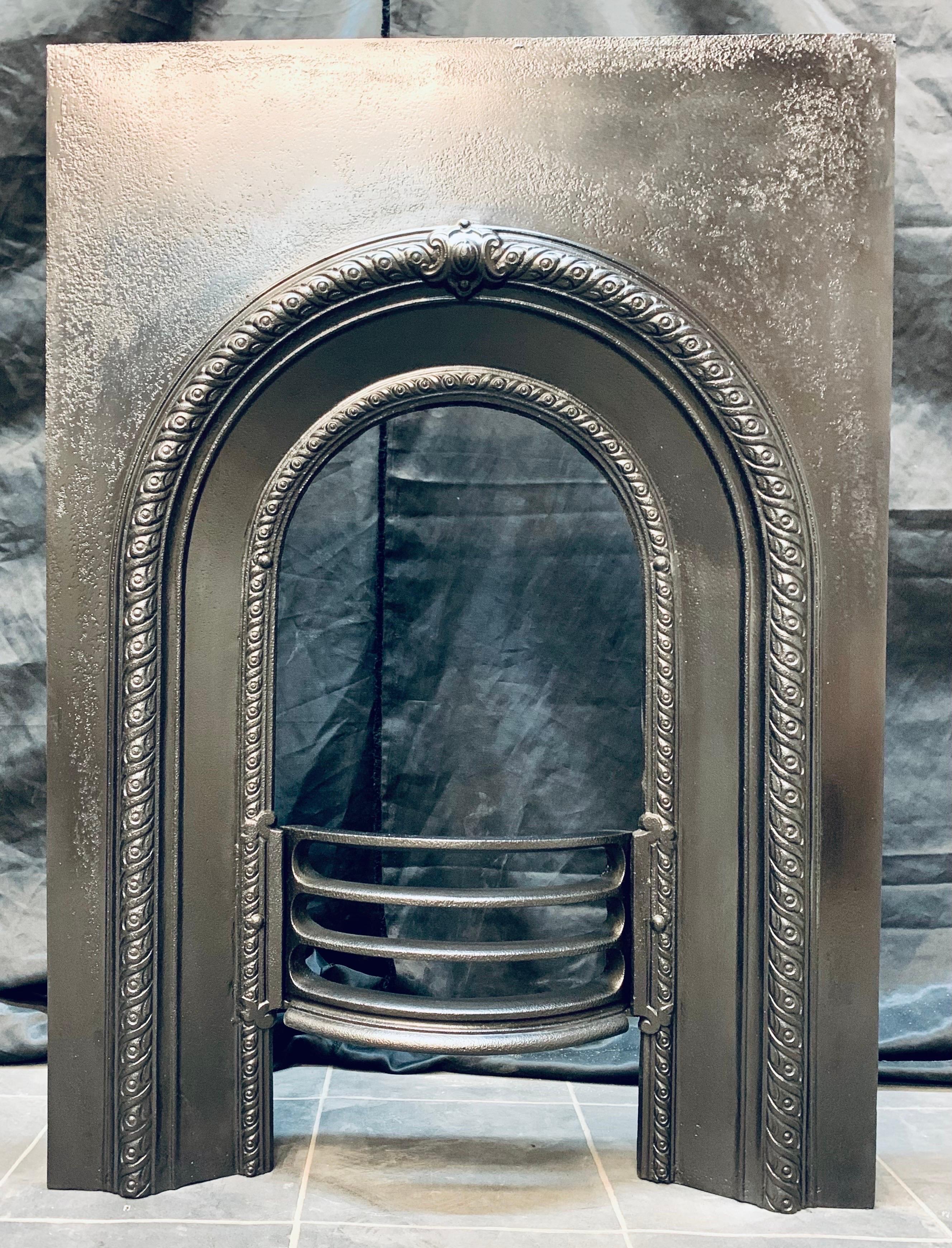 A small Scottish 19th Century Victorian cast iron fireplace insert, with a raised border and centralised cartouche, complete with its original curved fire bars. 

Scotland 1880c