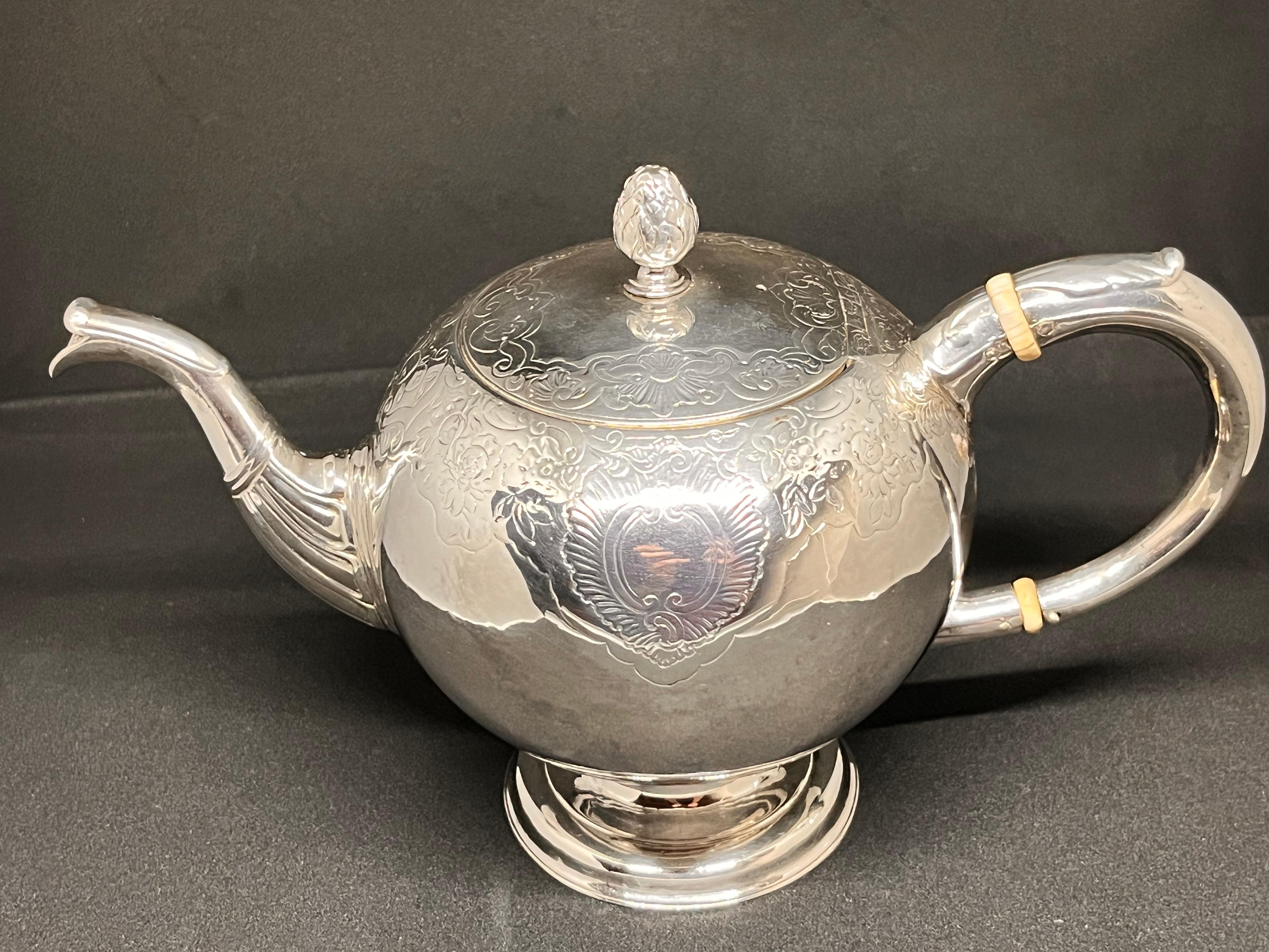 A splendid example of a George II Scottish silver teapot, of bullet shape, the body decorated with period flat chasing depicting fruit and flowers, with dual opposing vacant cartouche, atop a stepped, spreading circular foot, with short-form curved