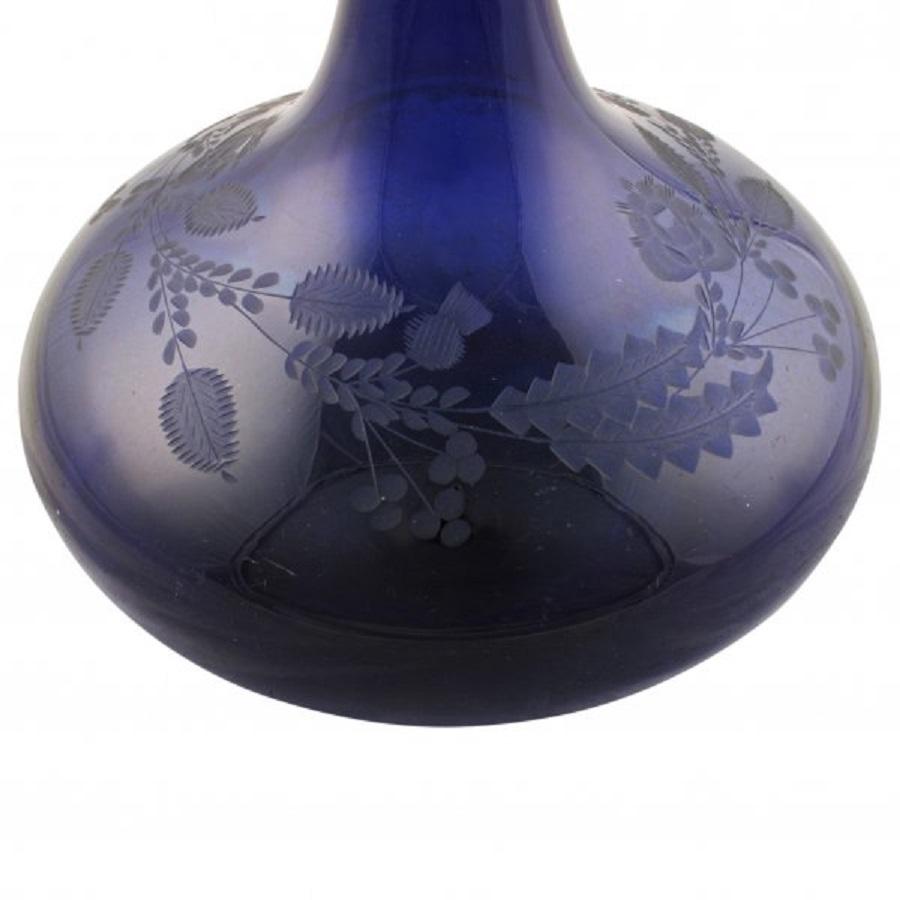 A middle of the 19th century Victorian Scottish Bristol blue glass decanter.

The decanter has a cork and metal stopper and is decorated with engraved thistles and flowers.

The cork stopper has a metal cap and a ring handle.

The decanter is