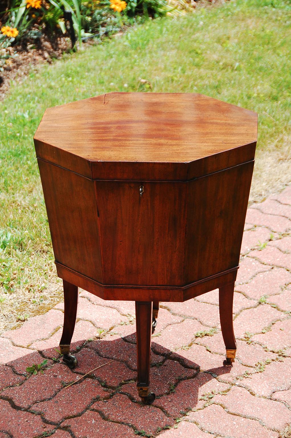 Scottish Georgian mahogany octagonal cellarette on original base. The tapered molded edge legs have an elegant curve to them as they sweep to the brass casters. The hinged top opens to reveal the remnants of the original lead liner. If one wants to