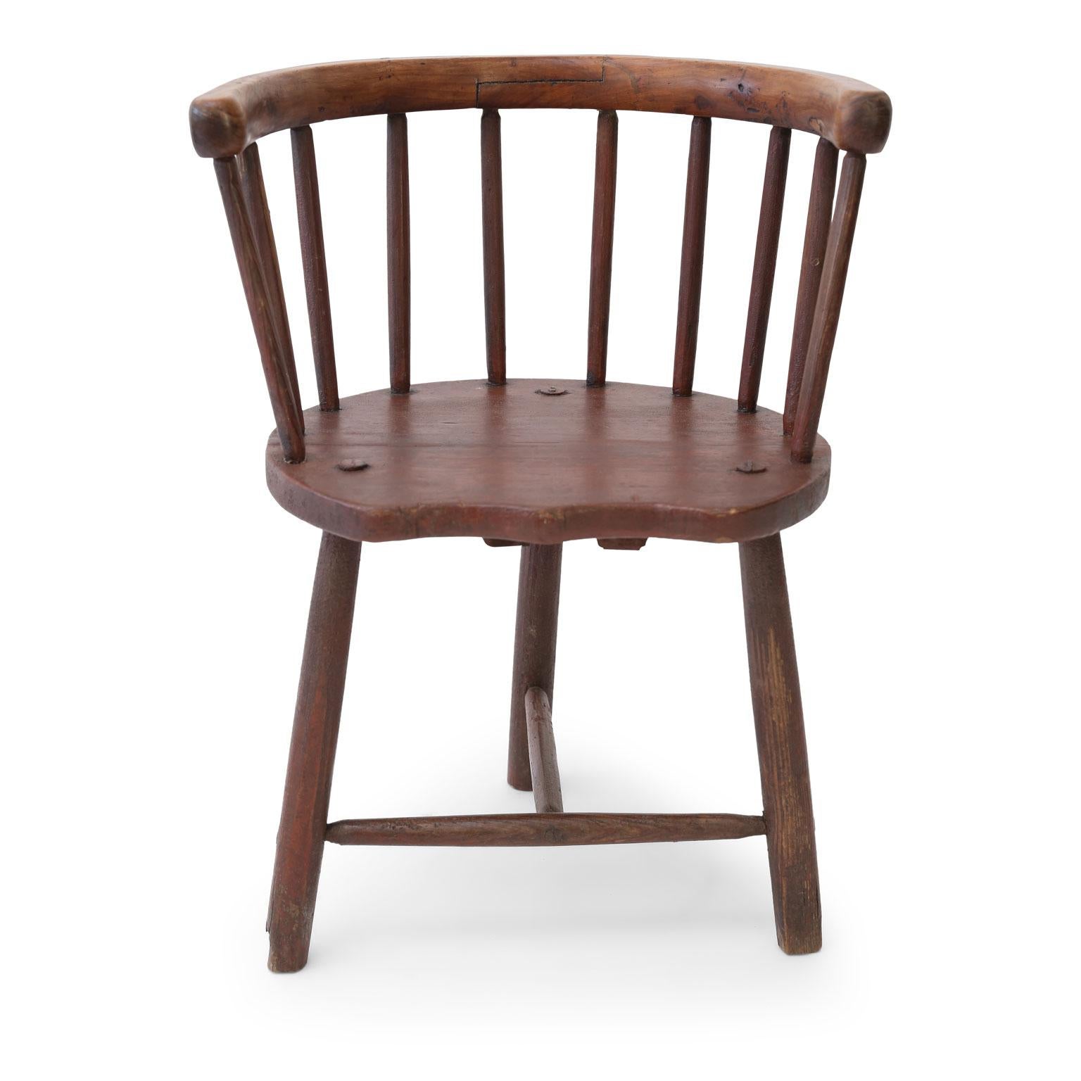 Scottish horseshoe-back chair, circa 1850-1870. This vernacular Windsor style stick-back chair from Argyll, Scotland, features pegged construction and remnants of original earthy red milk paint. Its seat is pine, legs and spindles are elm and the