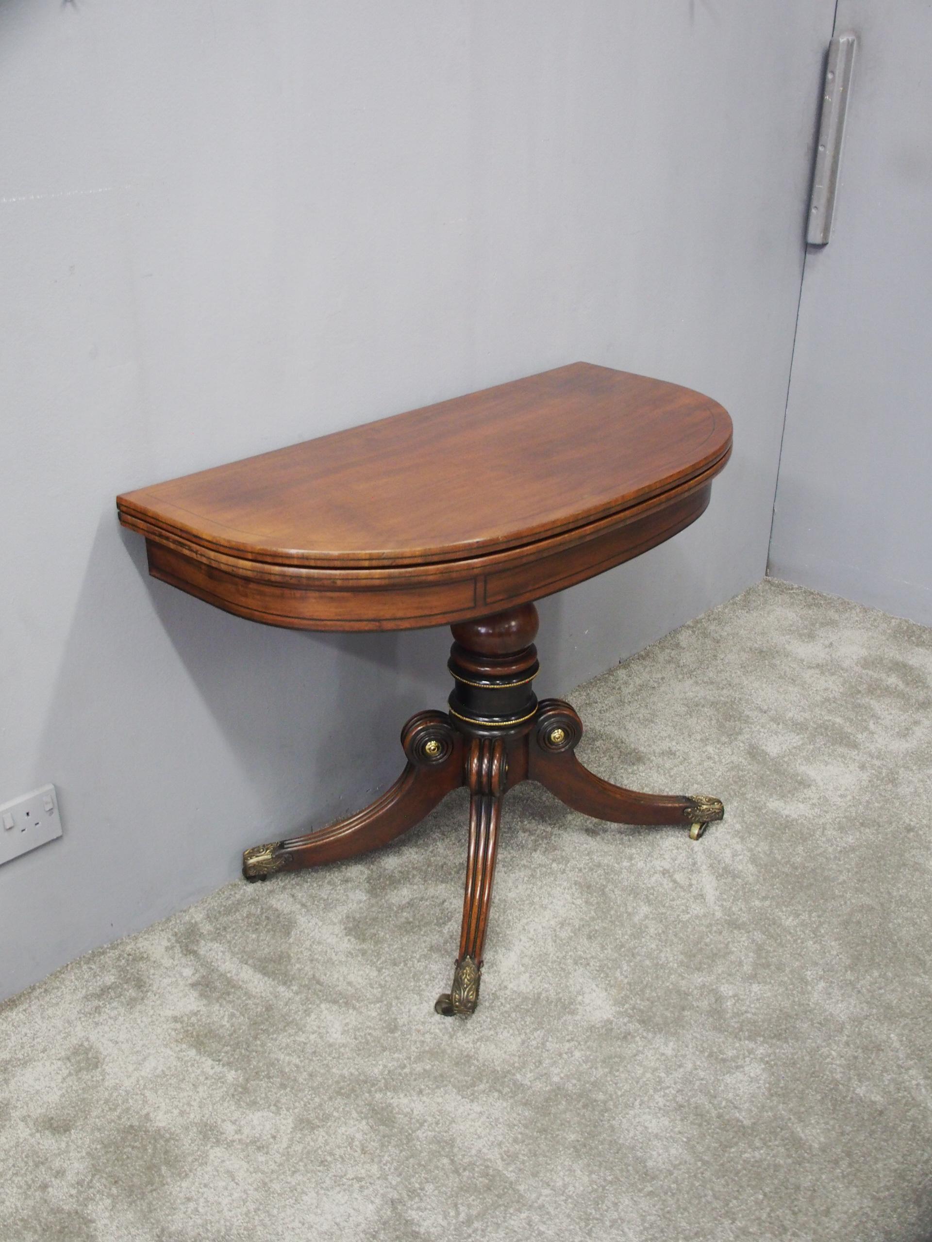 Scottish mahogany D shaped card table. With ebony string inlay to the front, the hinged top opens to reveal an inlaid interior and it has a frieze decorated with ebonized panels. The quadruple sabre leg base has ring turned sections, banded in
