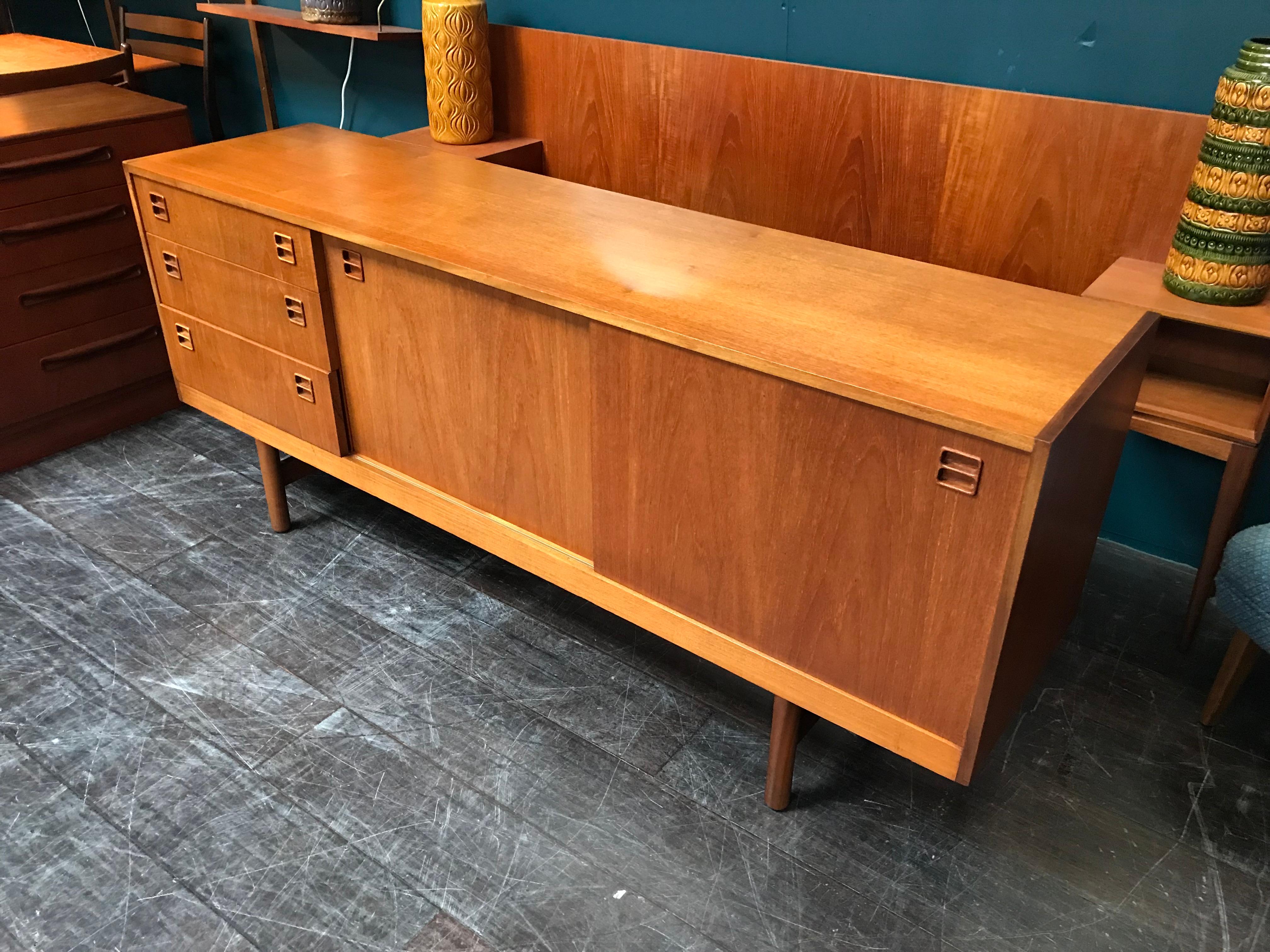 A rare and beautiful vintage midcentury sideboard by iconic Scottish furniture maker Beithcraft. With those desirable sliding doors this is such an elegant piece of furniture. Three drawers sit to the left of the cupboard doors, the top one with