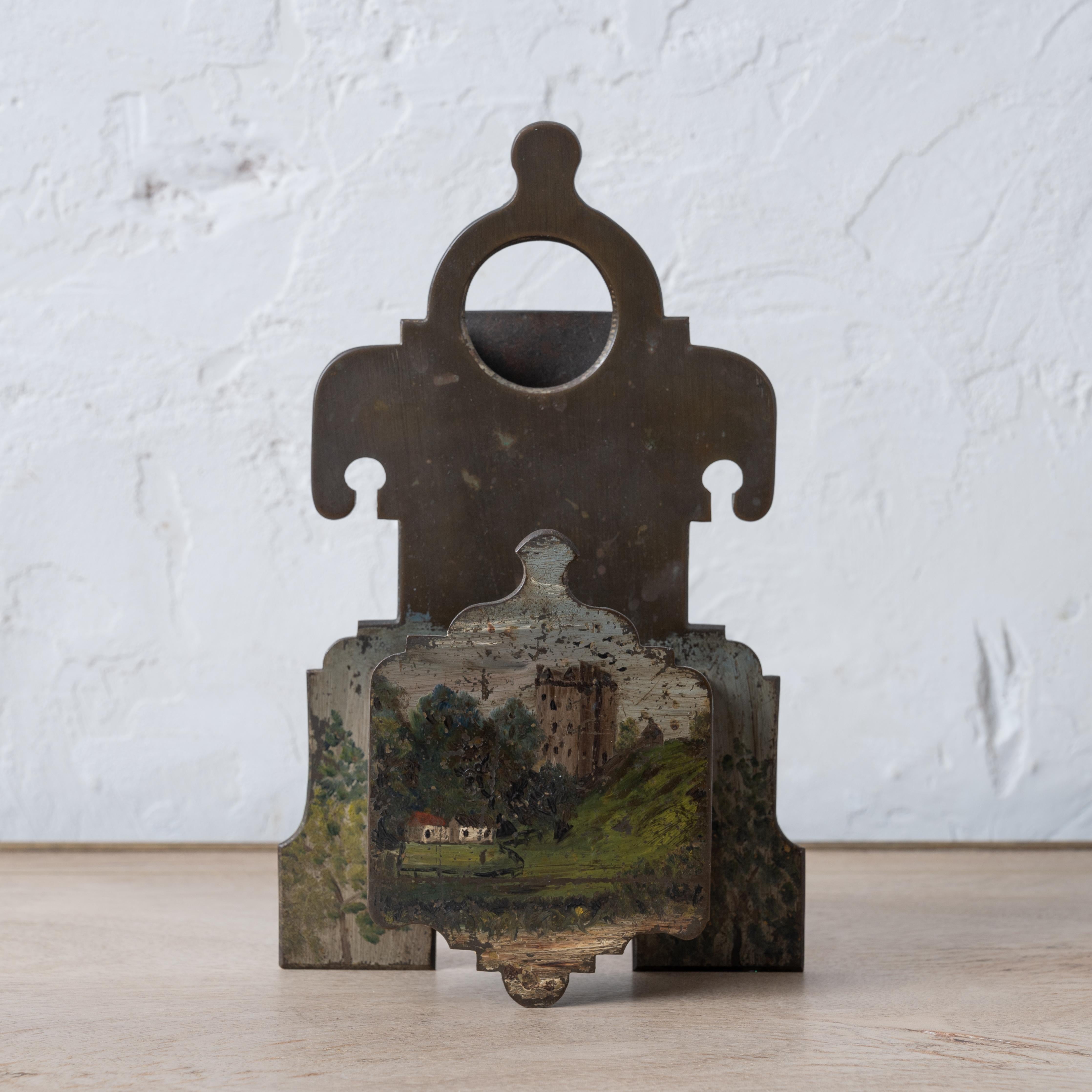 A Victorian brass match holder painted with Scottish castle and landscape, late 19th century.

6 inches wide by 2 inches deep by 9 ½ inches tall

