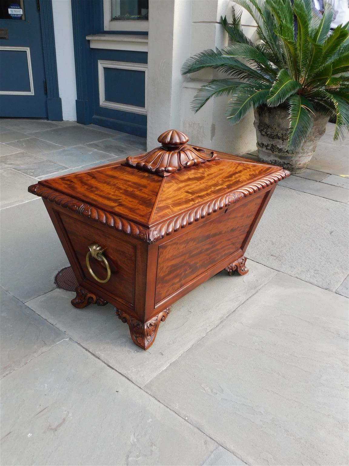 Scottish Regency mahogany hinged cellarette with foliage cartouche, gadrooned molded edge, original brass circular side handles, lead lined interior with stopper, and resting on carved foliage scrolled triangular feet with the original brass