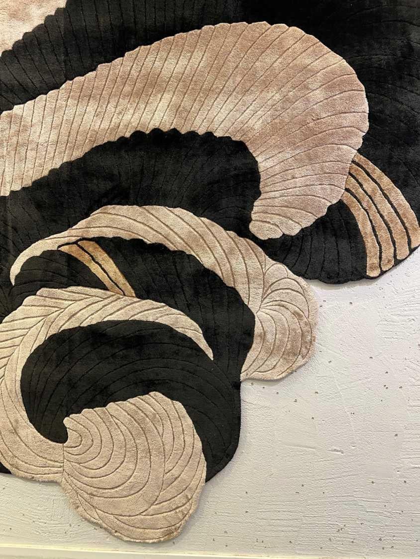 SCRAMBLE est un tapis dynamique et sculptural qui explore le mouvement, le contraste et la texture. Des tourbillons audacieux de noir, de beige et de tons dorés s'élèvent et retombent sur sa surface en formations superposées, semblables à des