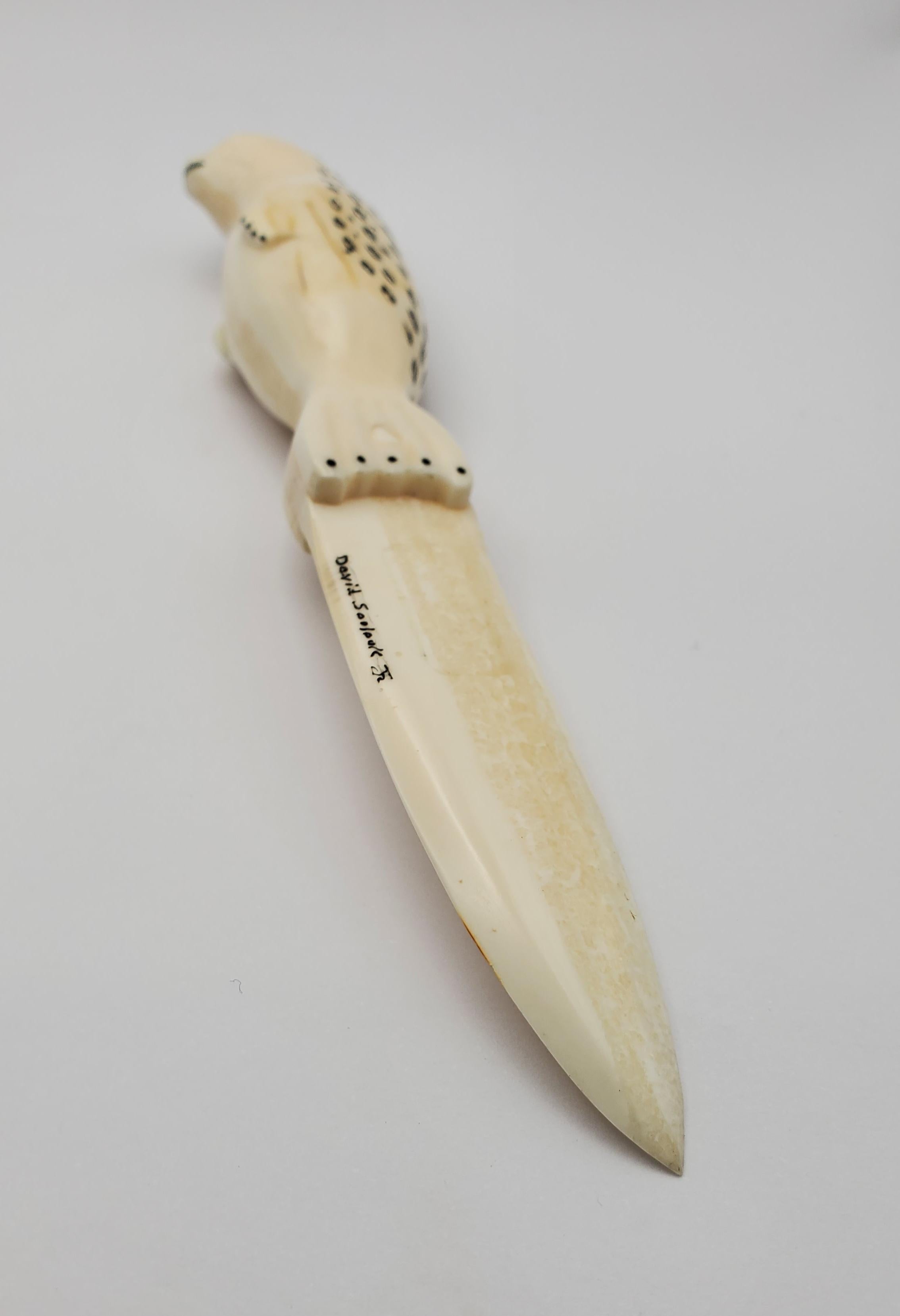 Magnifique couteau de cérémonie inuit en ivoire de morse sculpté scrimshaw représentant un charmant phoque tacheté par David JR.  La lame du couteau mesure 7,5 cm de long et est signée par l'artiste. Le couteau a environ 40 ans. La pièce est très