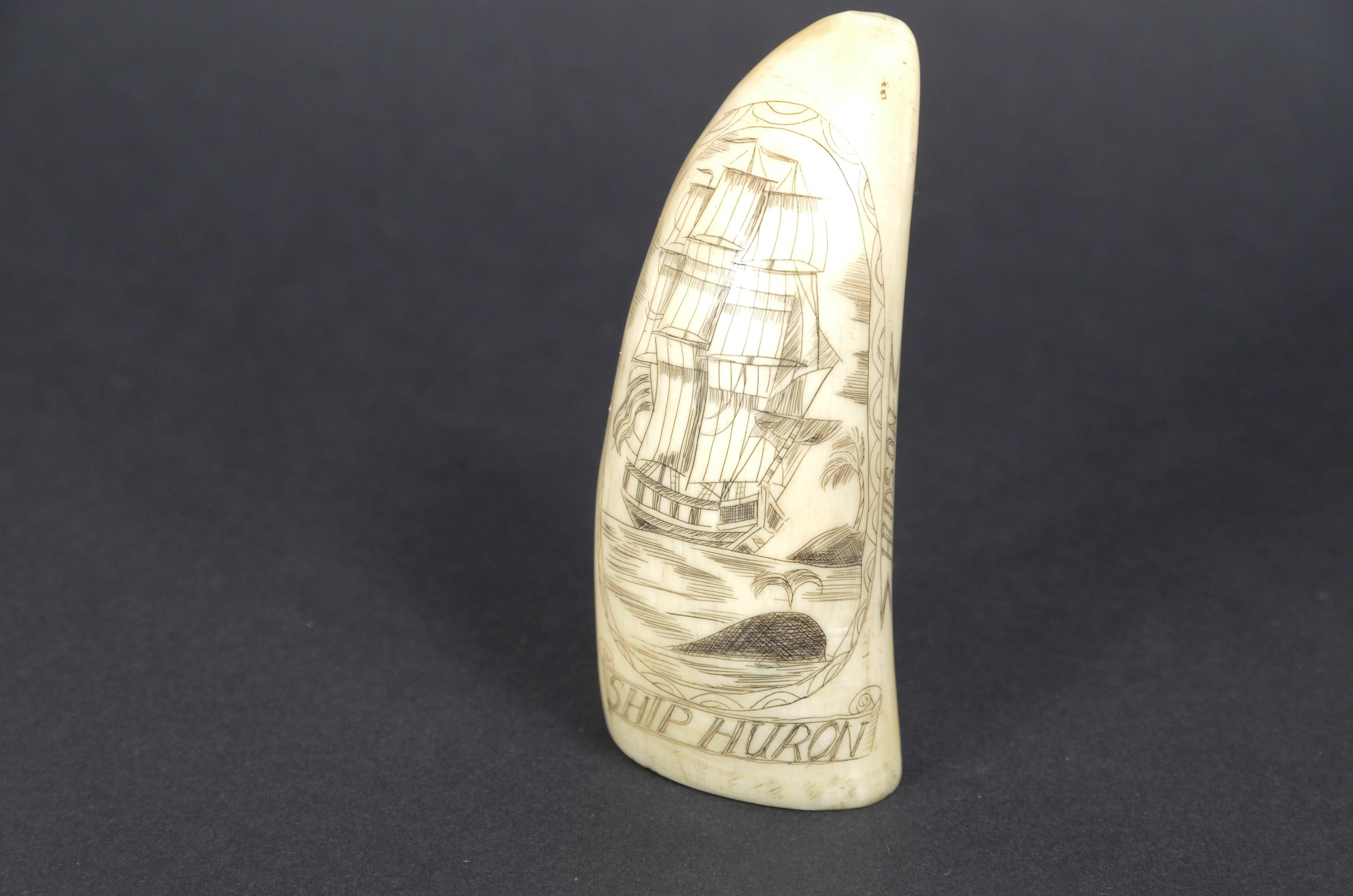Scrimshaw of a vertically engraved whale tooth, exquisite workmanship dated 1839, height  cm 9, depicting whaler near a rock and partially submerged whale, under the name of the ship SHIP HURON. On the sides and within a cartouche is engraved  the
