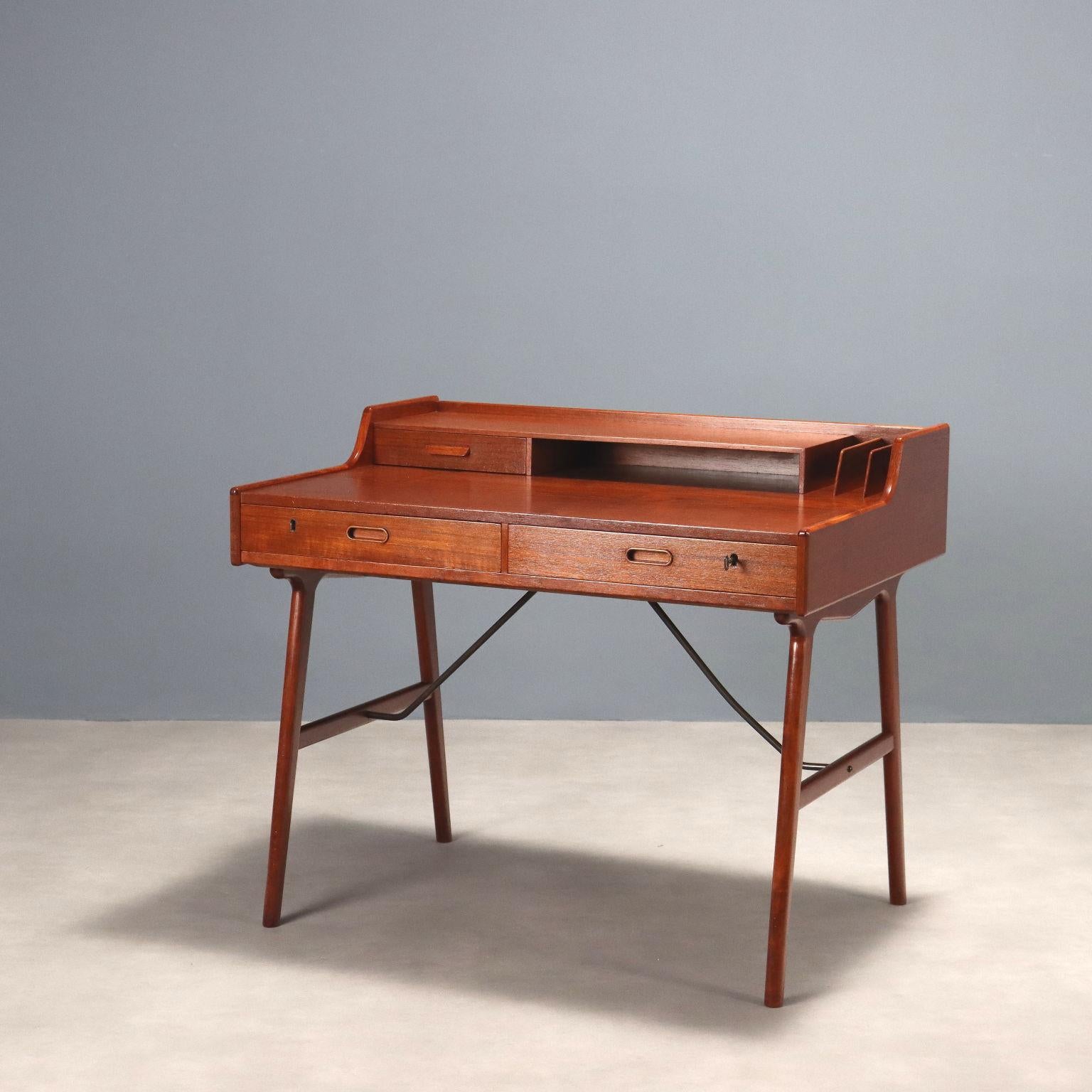 Bureau avec double tiroir sous le plateau et petite contremarche au-dessus du plateau. Bois plaqué teck, détails de construction soignés. 