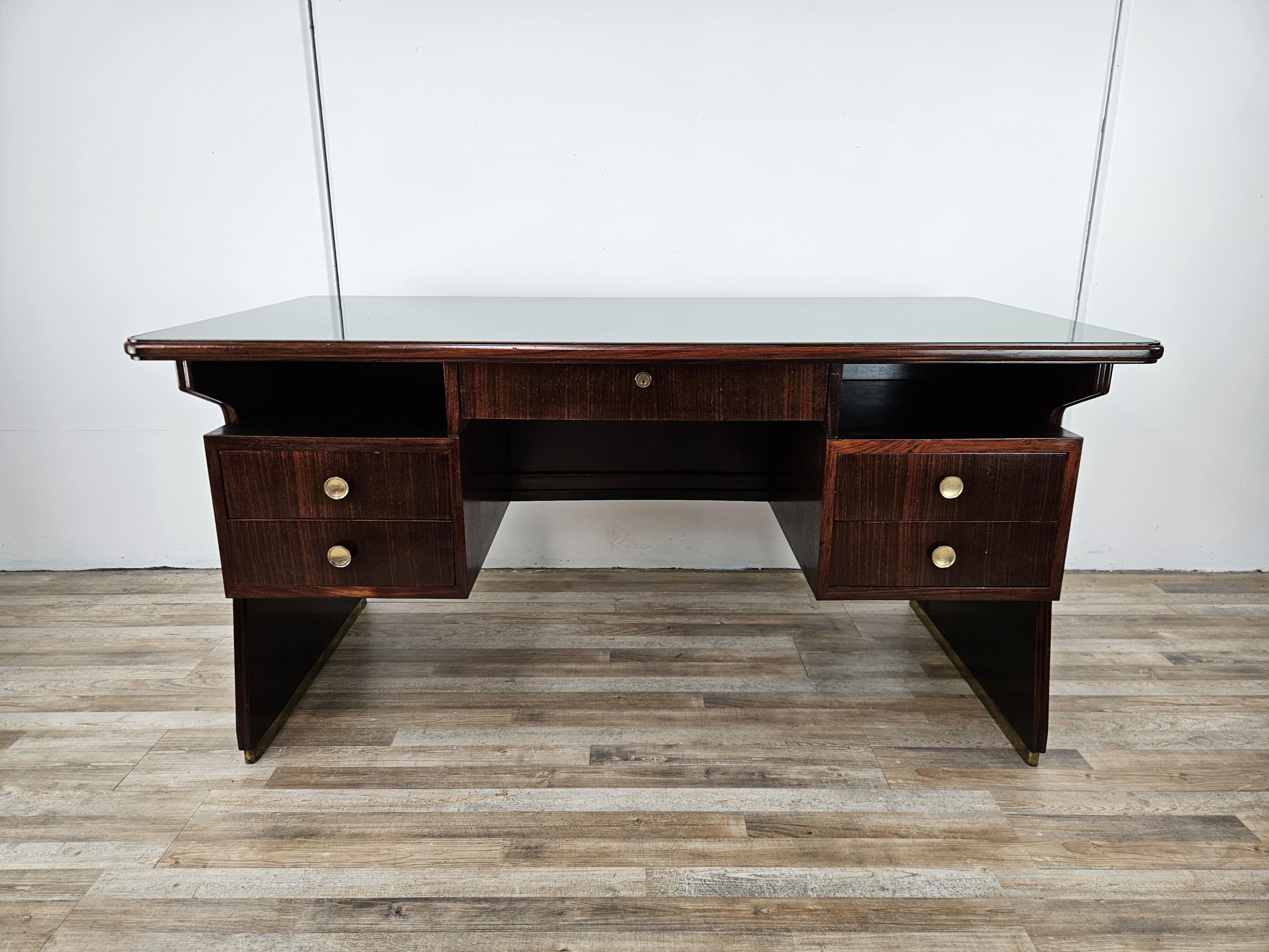 Important 1960s desk with exotic wood frame characterized by a refined geometric line, decorated with a profile at the base in brass.

The cabinet features an original period green glass top and brass knobs, desk enhanced by five large and sturdy