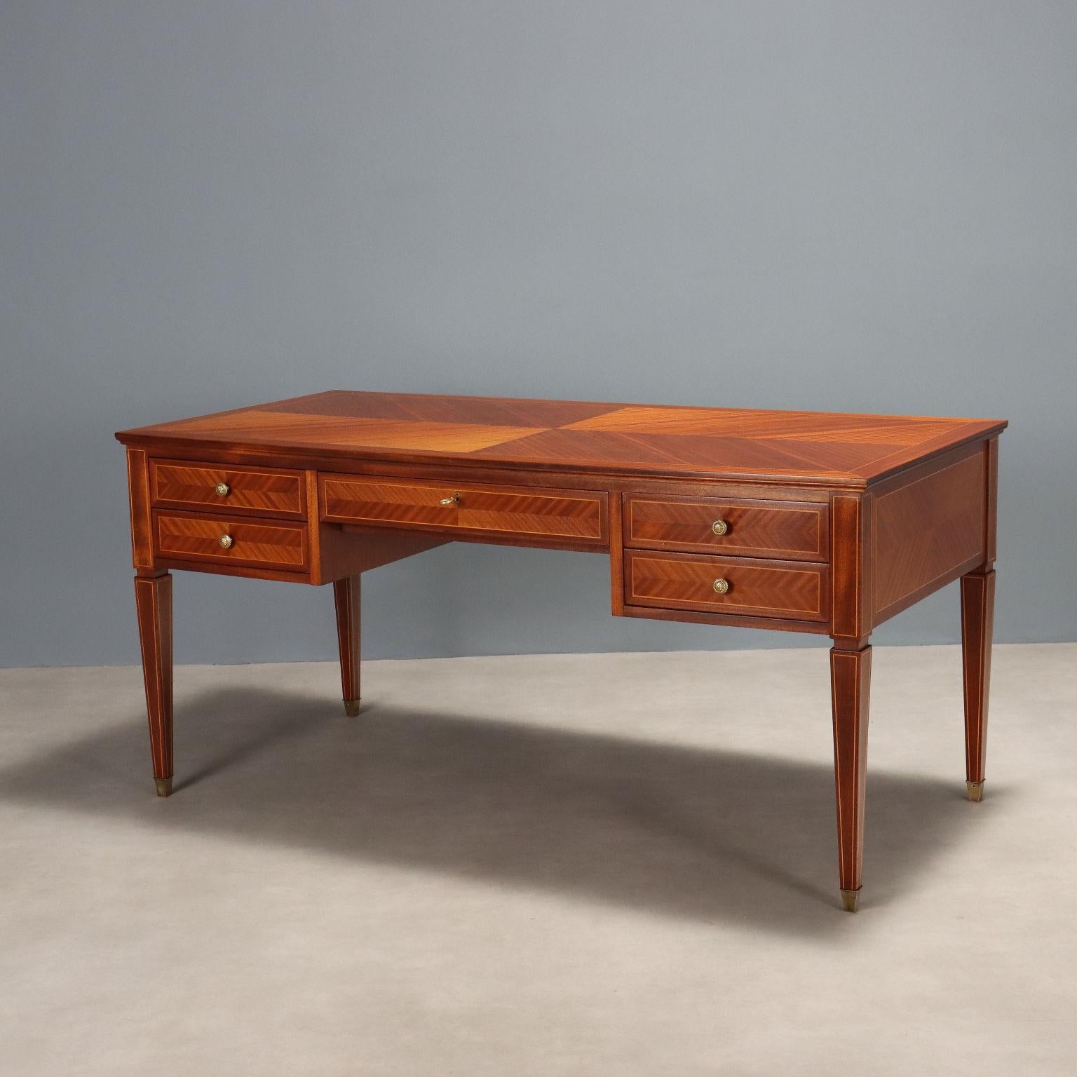 Elegant vintage Italian-made desk with mahogany veneer, features a rectangular top embellished with inlaid threading, a total of five drawers with brass handles. Truncated conical legs, also threaded, brass finials. Furniture restored to the