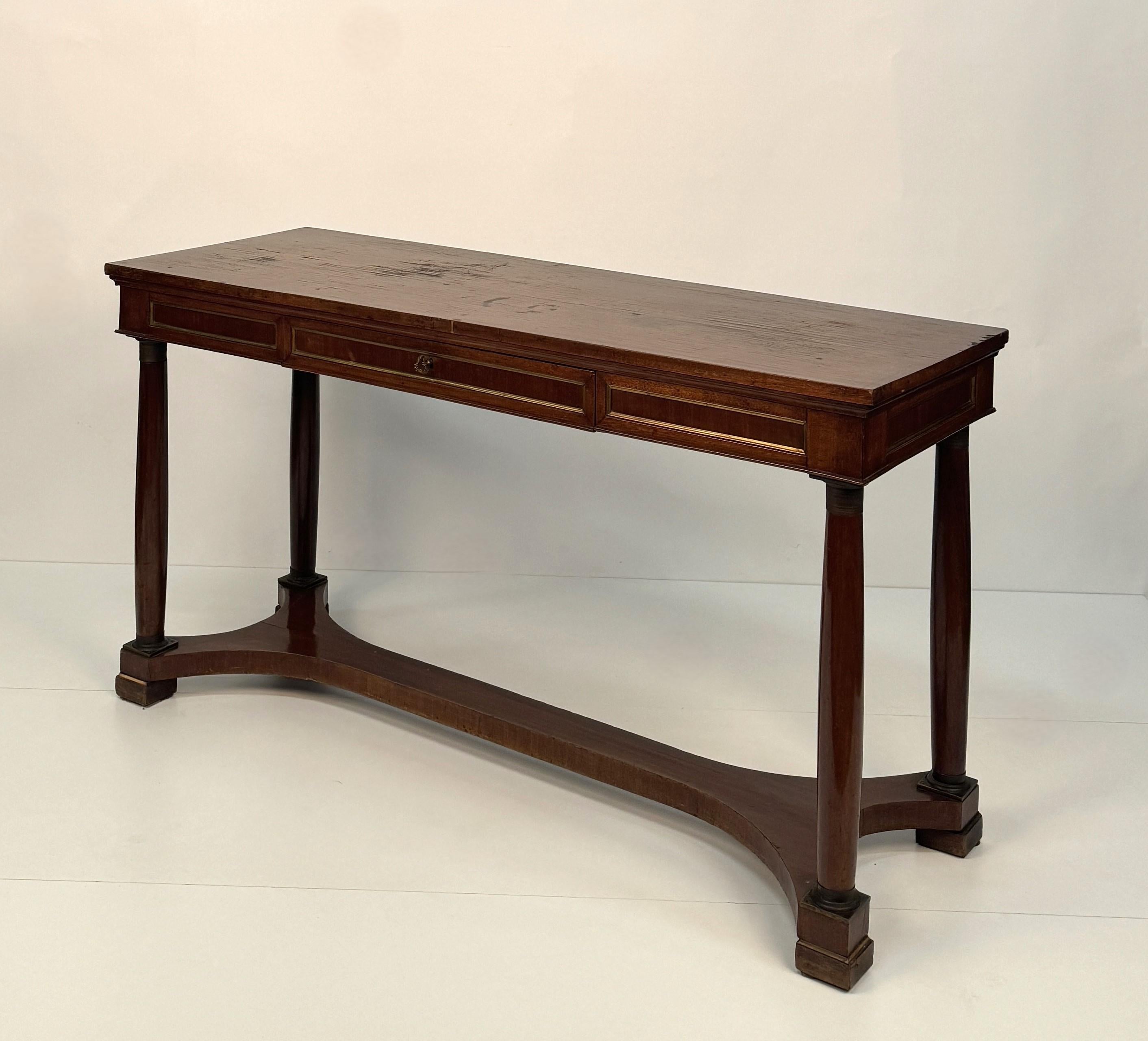 in the straight single-drawer belt decorated with gilt profiles like the panels decorating the sides and opposite side, column legs with metal capitals and base, joined by a molded crossbar,
cm 75x141x51