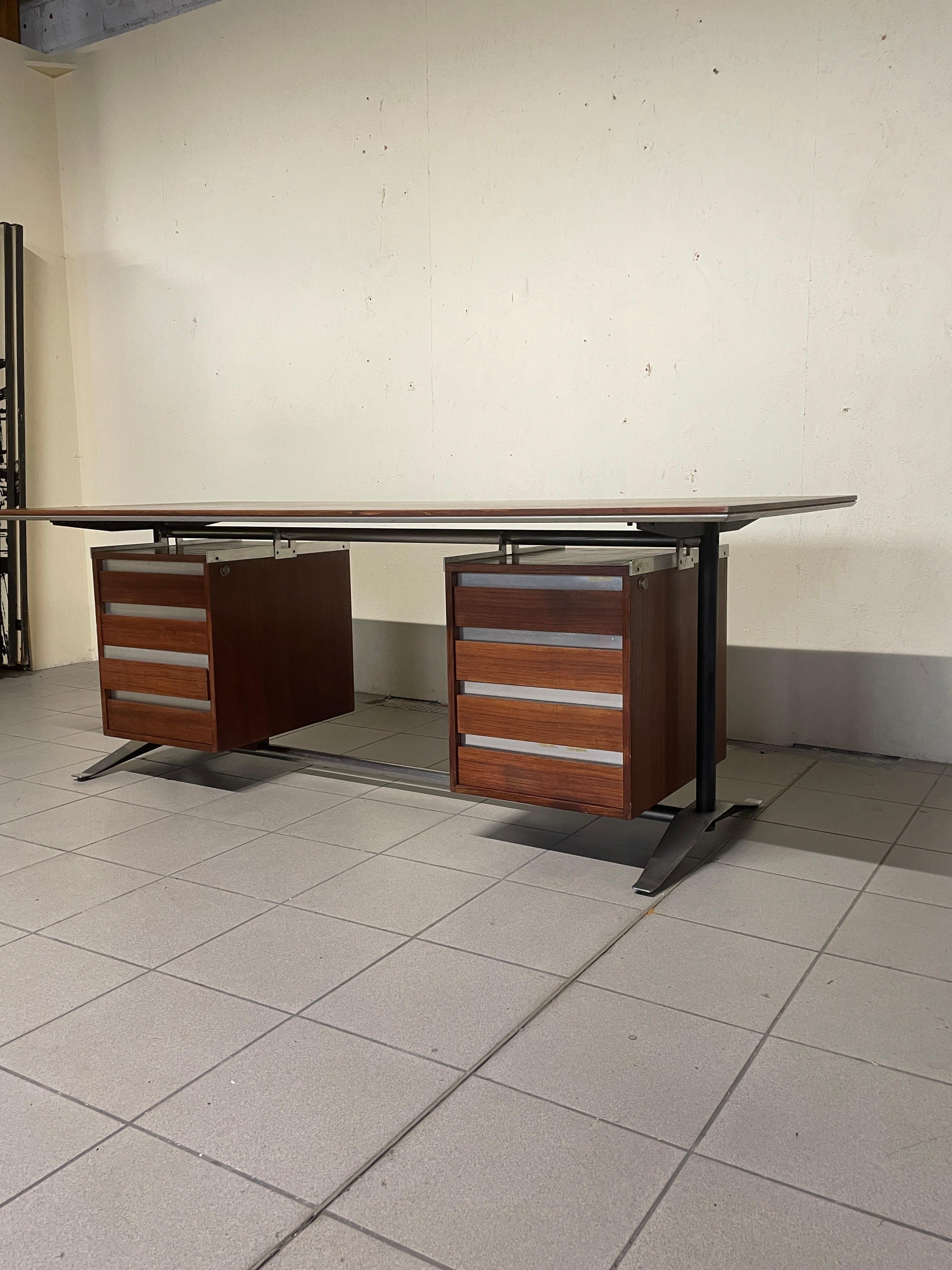 Schreibtisch für Führungskräfte, entworfen von Alberto Rosselli für das italienische Unternehmen Arflex im Jahr 1961.

Der Schreibtisch besteht aus einem verchromten und emaillierten Metallgestell und einer furnierten Holzplatte, die von zwei