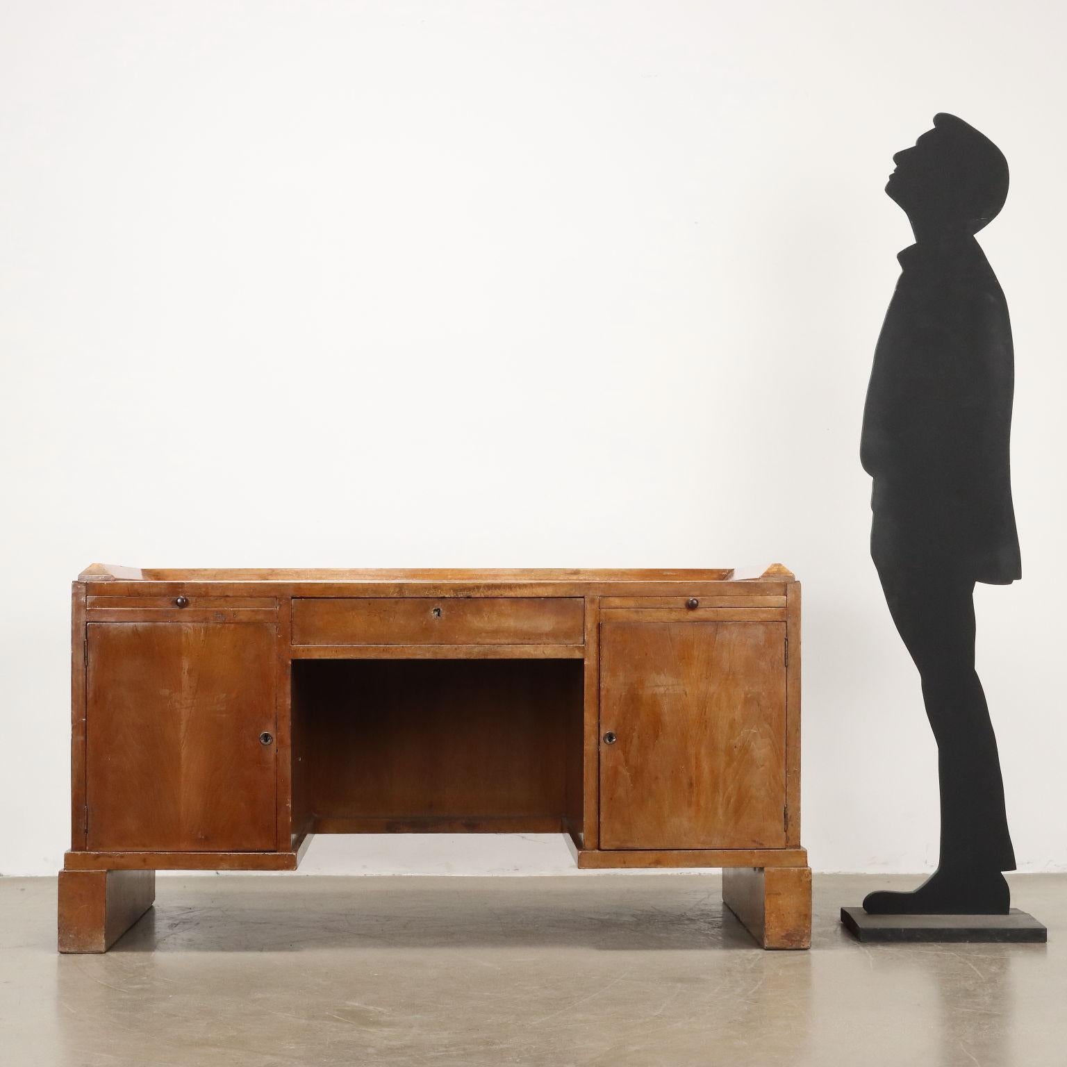 Elegante scrivania con cassetto centrale e coppia di tiretti laterali, vani contenitori con anta battente, legno impiallacciato noce. Discrete condizioni.