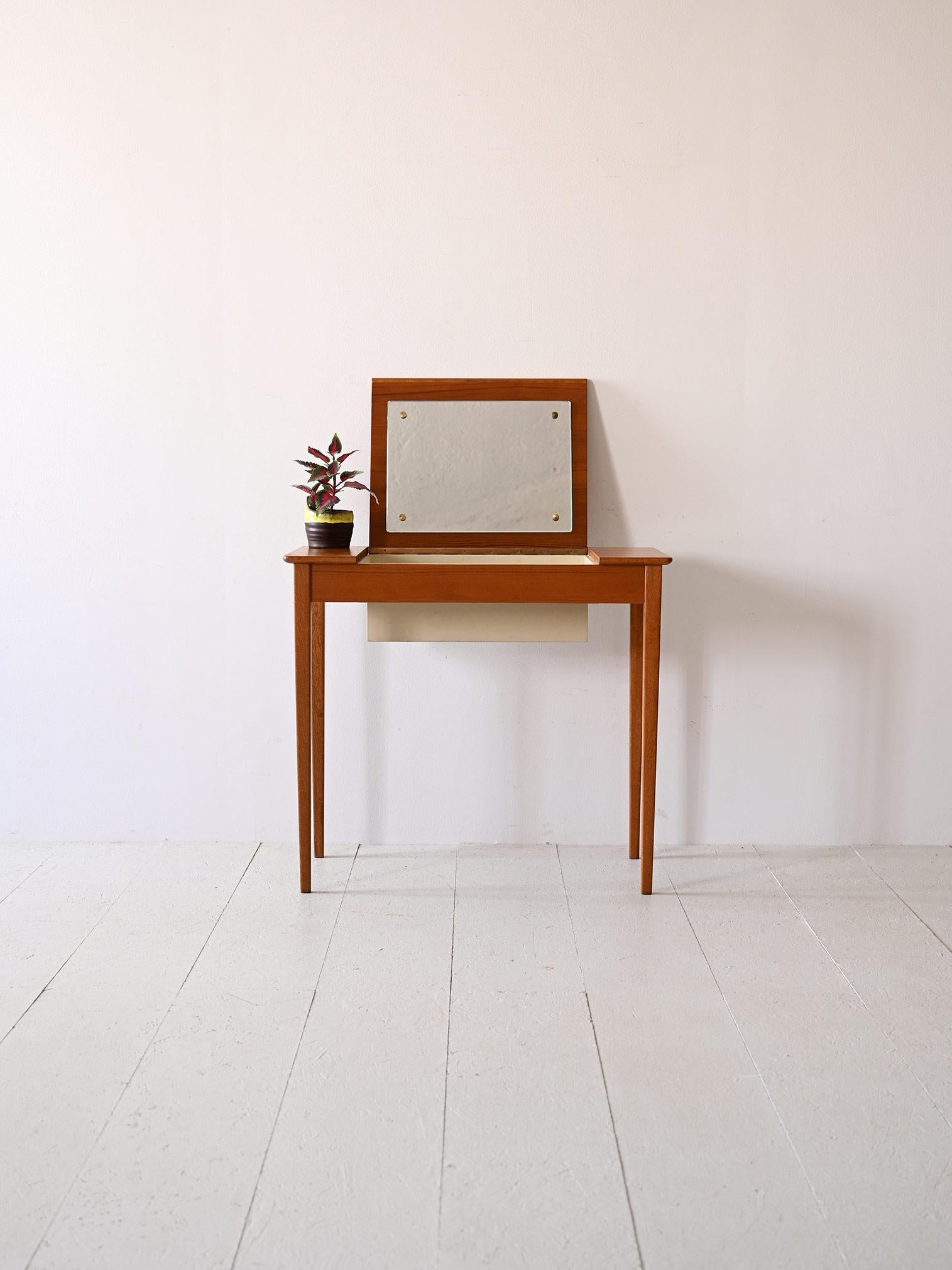 Nordic-made dressing table/desk from the 1960s with drop-down top.

Scandinavian teak furniture that combines aesthetics and functionality.
This small dressing table is distinguished by a flip-top that has a mirror on the inside. A convenient