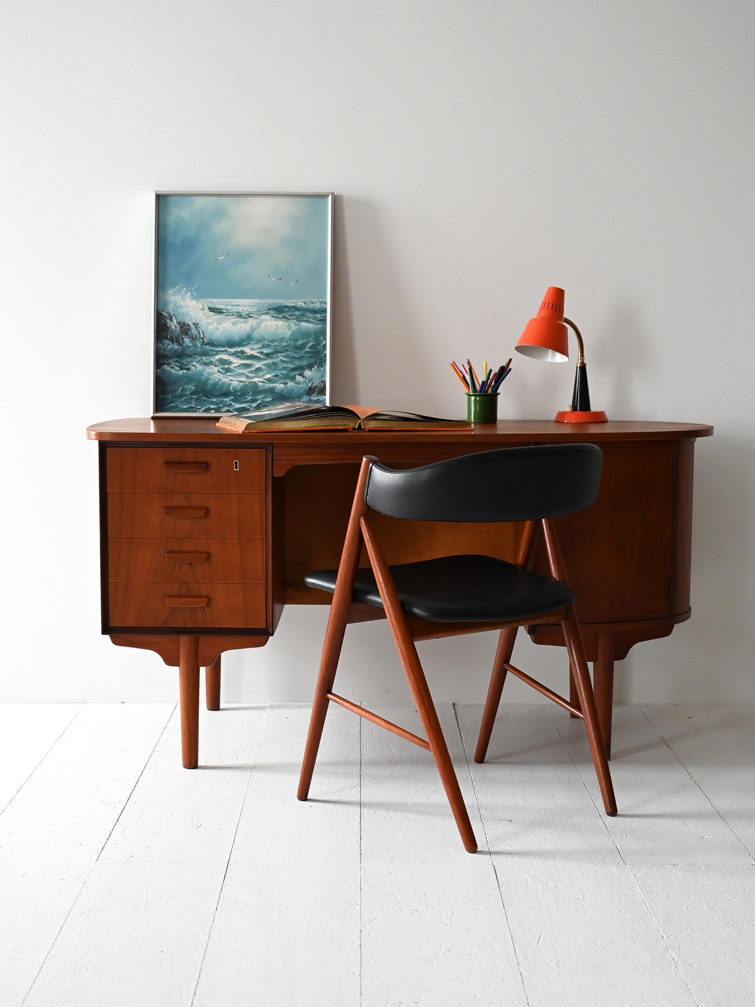 Scrivania vintage in teak con struttura ovale, quattro cassetti, anta a battente e libreria posteriore integrata.

Scrivania scandinava degli anni ’60 in teak, con struttura ovale e design pensato per essere posizionato liberamente nello spazio. Il
