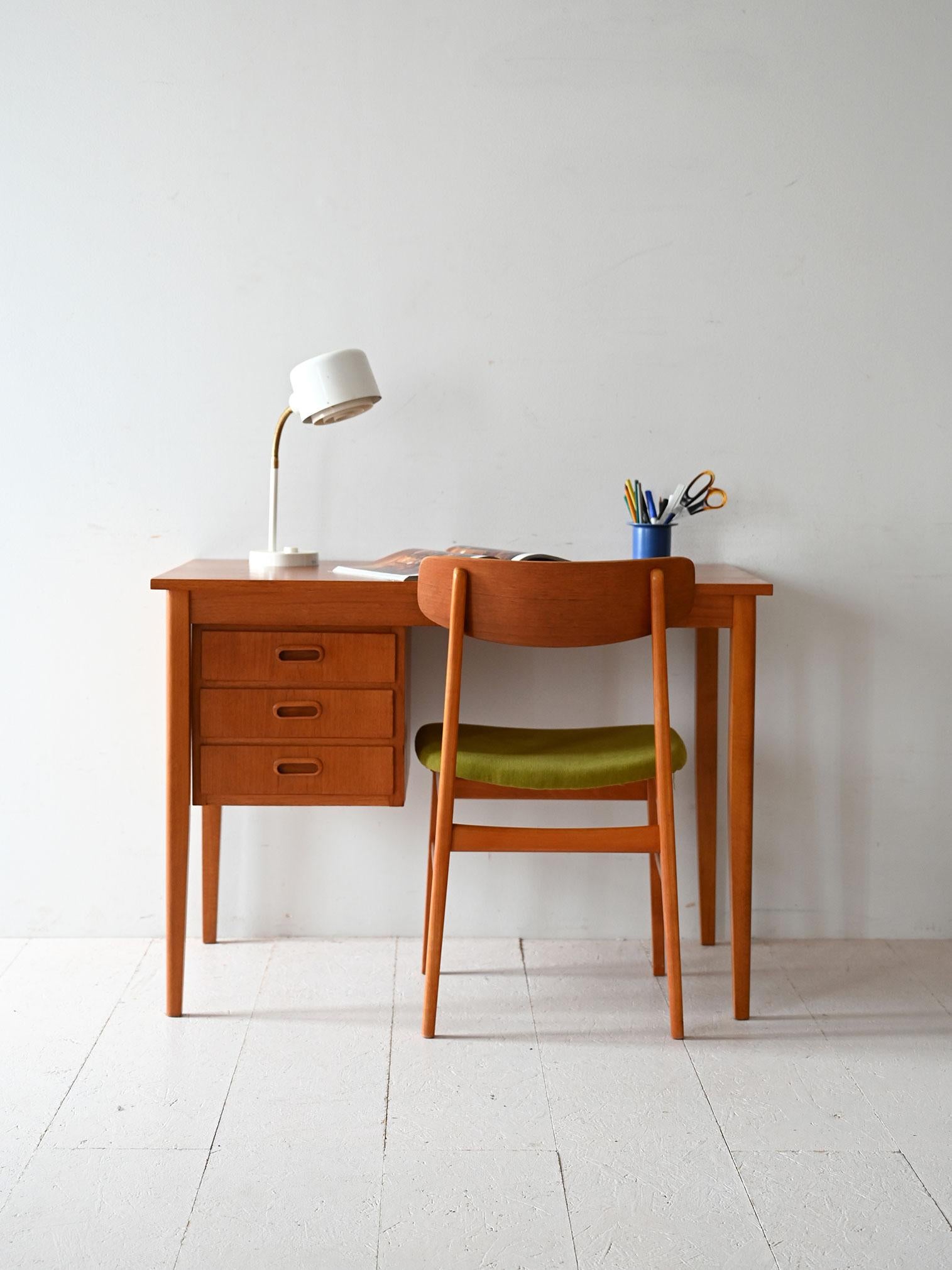 1950s/60s desk with tapered legs, three built-in drawers and clean lines in natural teak.

Vintage Scandinavian desk made of teak in the 1950s/60s. The design is basic, with three drawers lined up on the side and recessed handles. Tapered legs