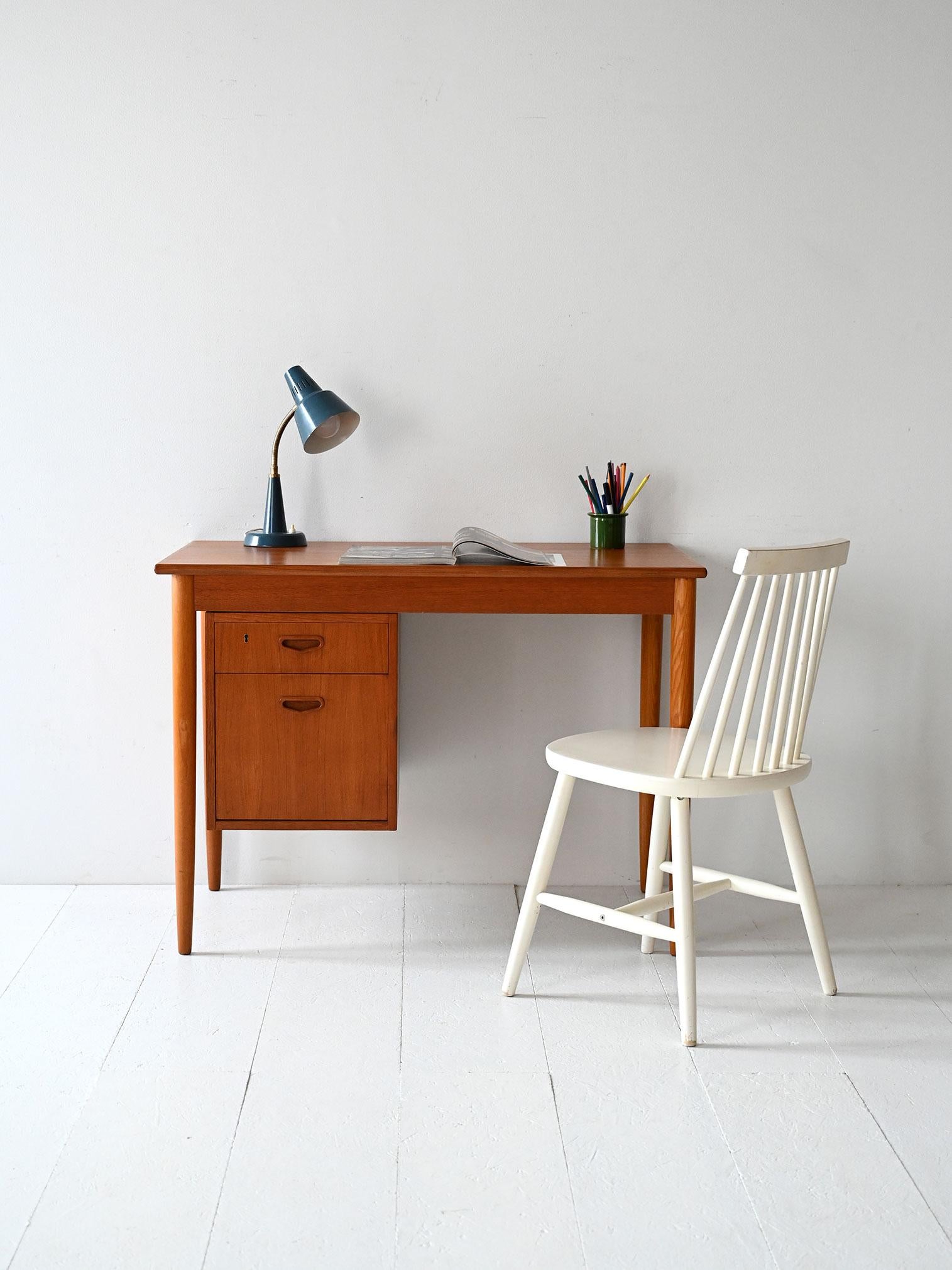 1950s teak desk with turned legs and sliding drawer block that can be positioned left or right.

Scandinavian 1950s desk made of teak with flamed grain. The legs are turned and slender, while the drawer block slides on rails and can be positioned on