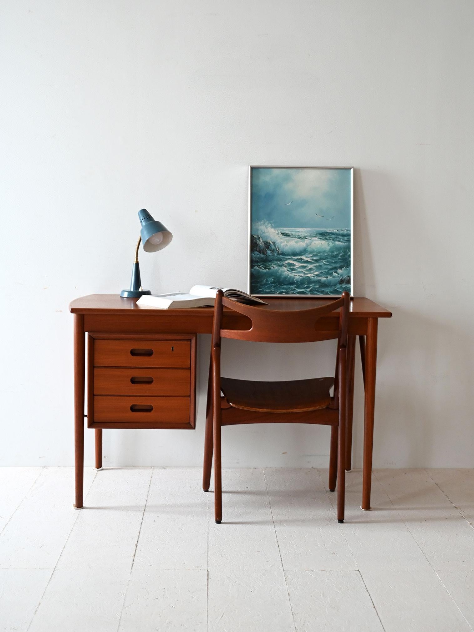 1950s/60s teak desk with three-drawer side block and elegant construction details.

Vintage Scandinavian desk dating from the 1950s/60s, made of teak with slender legs and exposed side reinforcements. The side block houses three drawers with