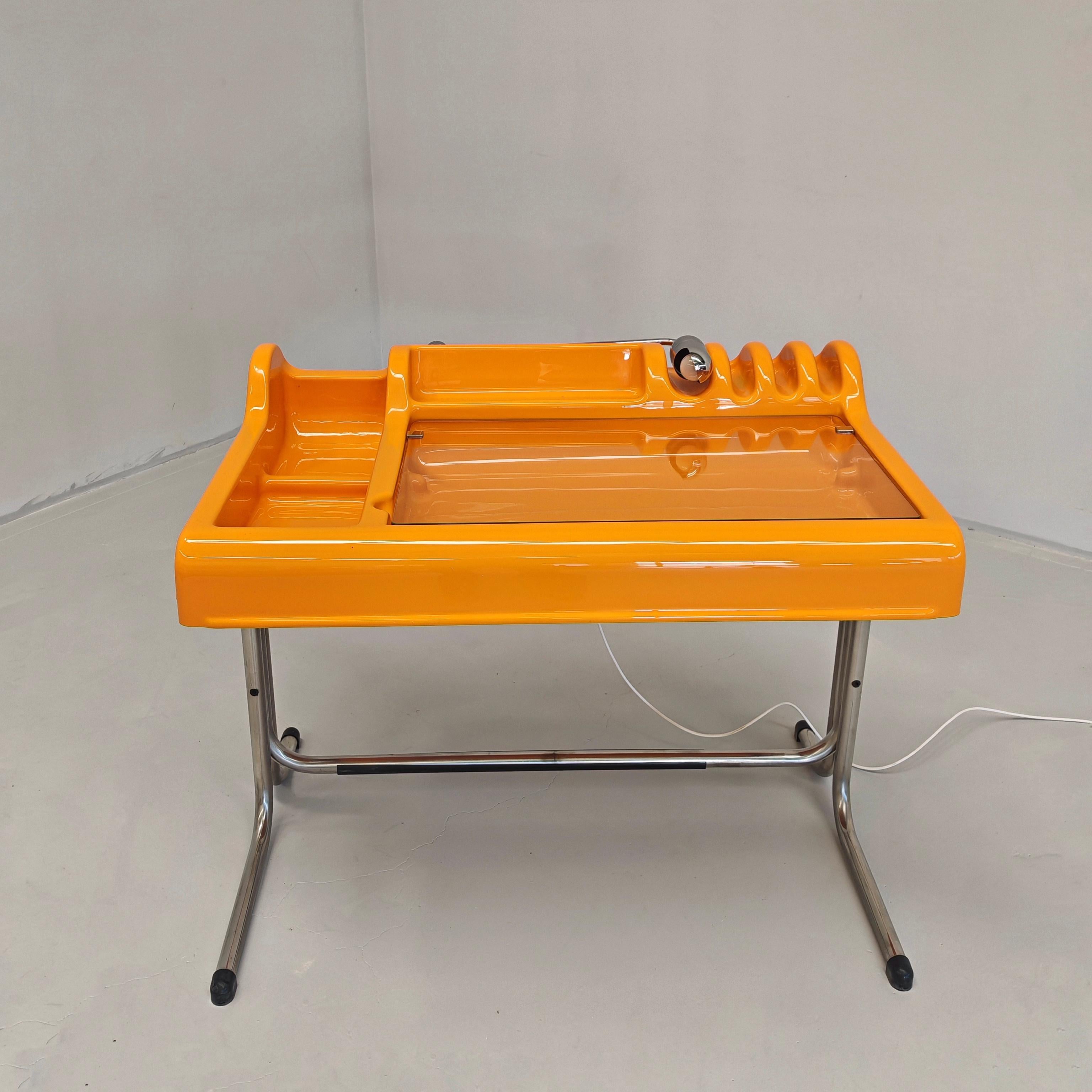 icónico escritorio vintage de diseño de la era espacial modelo Orix diseñado por Vittorio Parigi y Nanni Prina, fabricado por Molteni 1971. Tapa de plástico ABS de color naranja, marco de acero cromado, tapa de cristal transparente basculante y