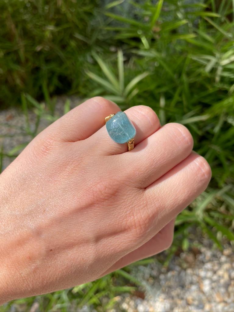 This antique style ring by Scrives is set with a large tumble aquamarine of 13.31 cts. The stone is natural and not treated. It shows visible natural inclusions.  
The stone is drilled at its center and a gold wire is going through it ending on each