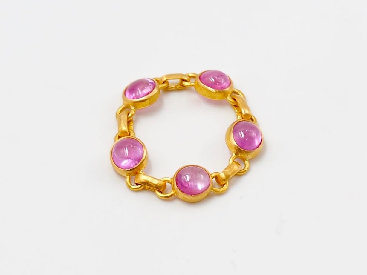 This ring by Scrives is made of 5 pink sapphire cabochons set in 22 karat Gold. The colour of the sapphire is  strong pink / hot pink. The sapphires are natural and untreated from Myanmar / Burma. 
The ring is like a chain, flexible and very