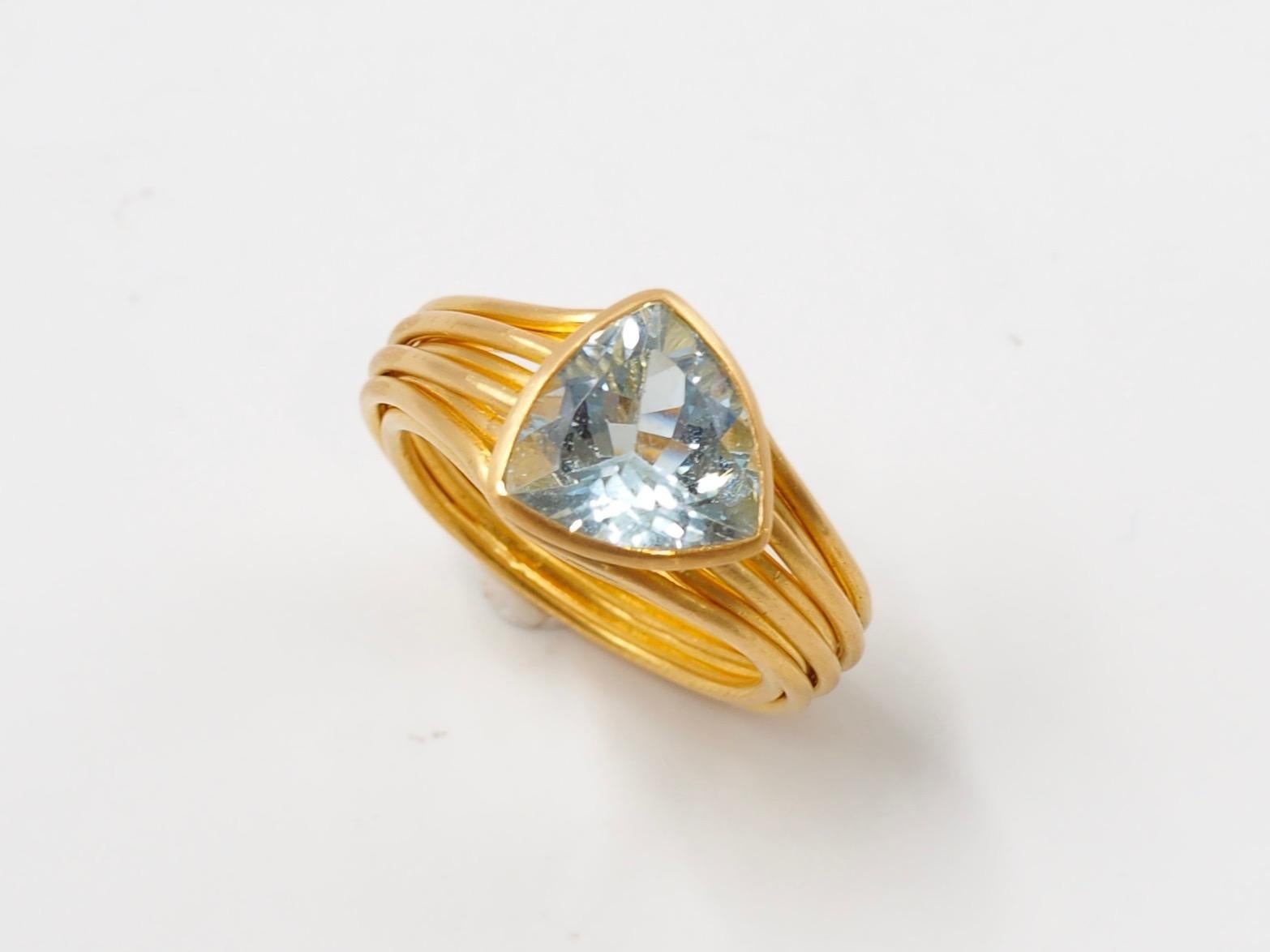 This ring by Scrives is made of ten 22 karat gold wires of 1mm thickness running around an aquamarine of 5.2 carats in a shape of a trillion. 

The stone shows minor and non visible natural and typical inclusions (no treatment).
 
This one-of-a-kind
