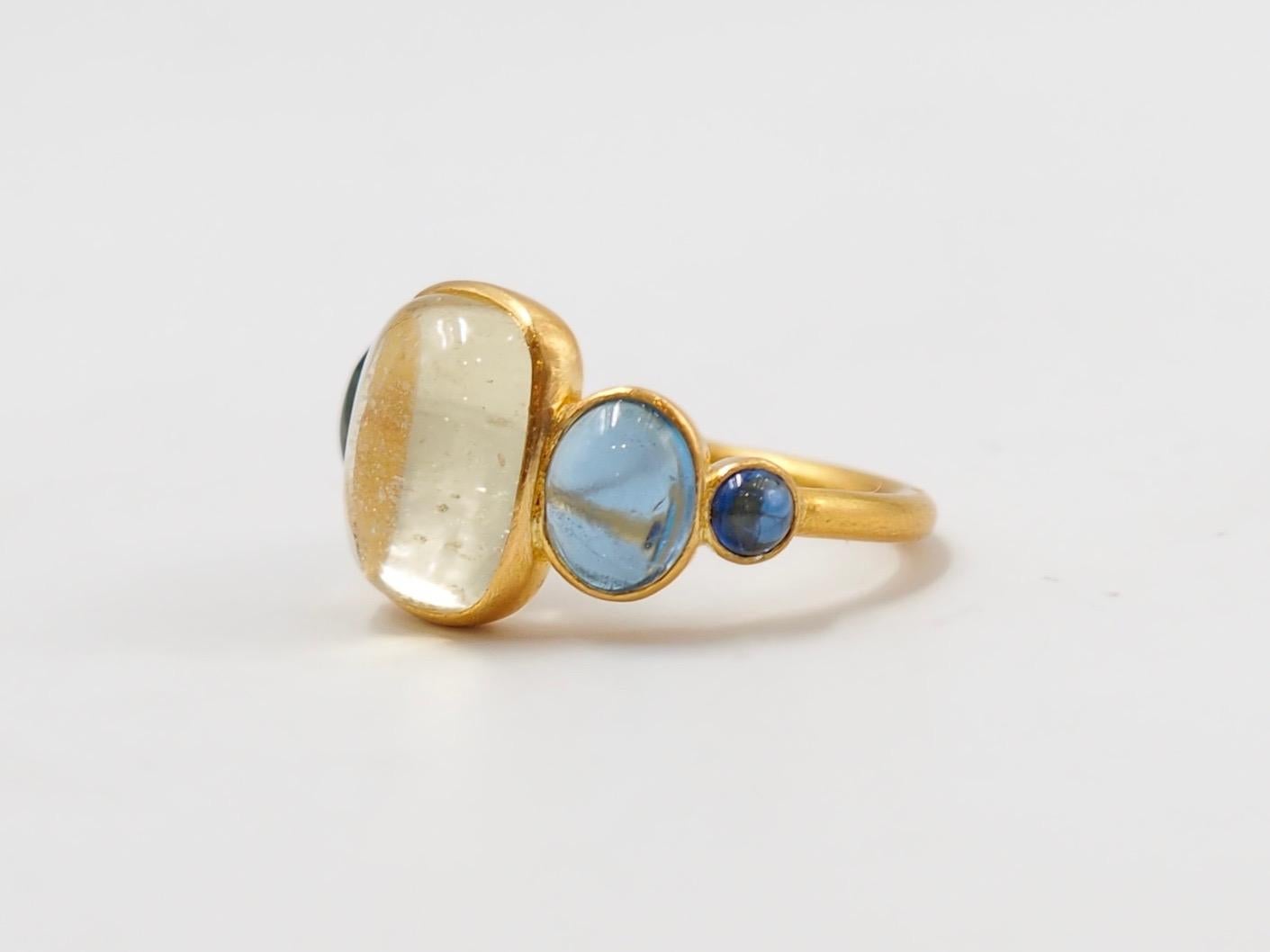 This delicate ring is composed of 5 stones in line: 1 natural yellow beryl cabochon called heliodor, 2 natural aquamarine cabochons and 2 blue sapphire cabochons. The center stone is an heliodor of 5.3 cts and the 2 aquamarines have a total weight