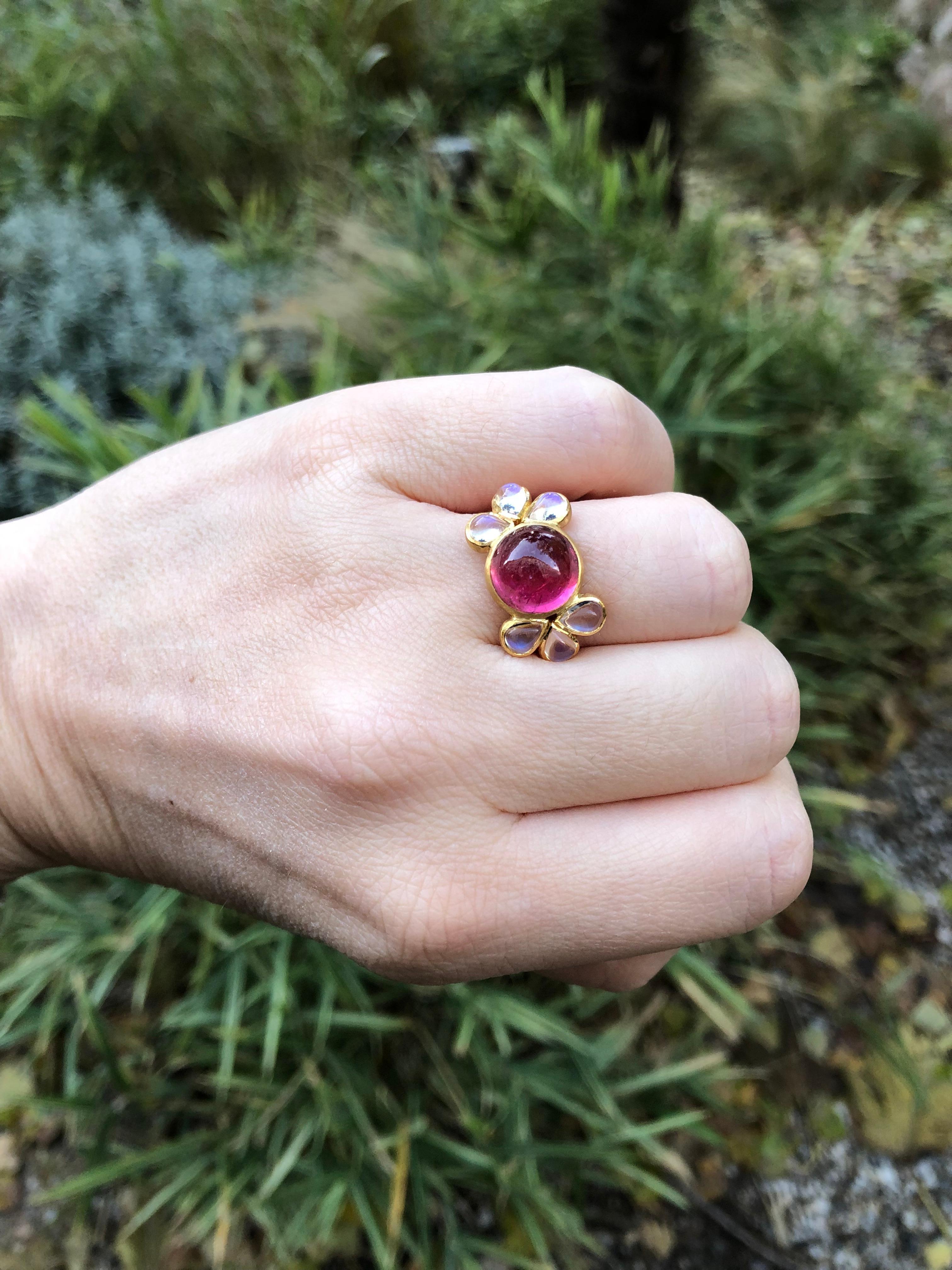 This delicate ring is composed of an intense Pink Tourmaline cabochon of 5.56 cts surrounded by 6 moonstones cabochons (total weight: 2.08cts). The pink tourmaline is natural with typical inclusions with a juicy pink colour (the photos taken outside