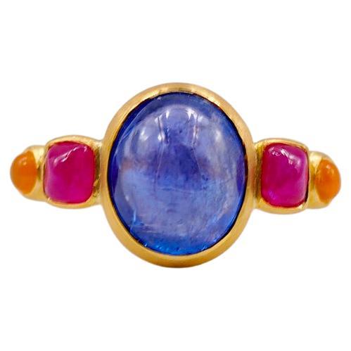 This delicate ring is composed of 5 stones in line: 1 tanzanite cabochon, 2 natural rubies sugarloaf cabochons and 2 cornaline cabochons. The center stone is a tanzanite of 6,06 cts and the 2 rubies have a total weight of 1.06 cts. The 2 cornalines